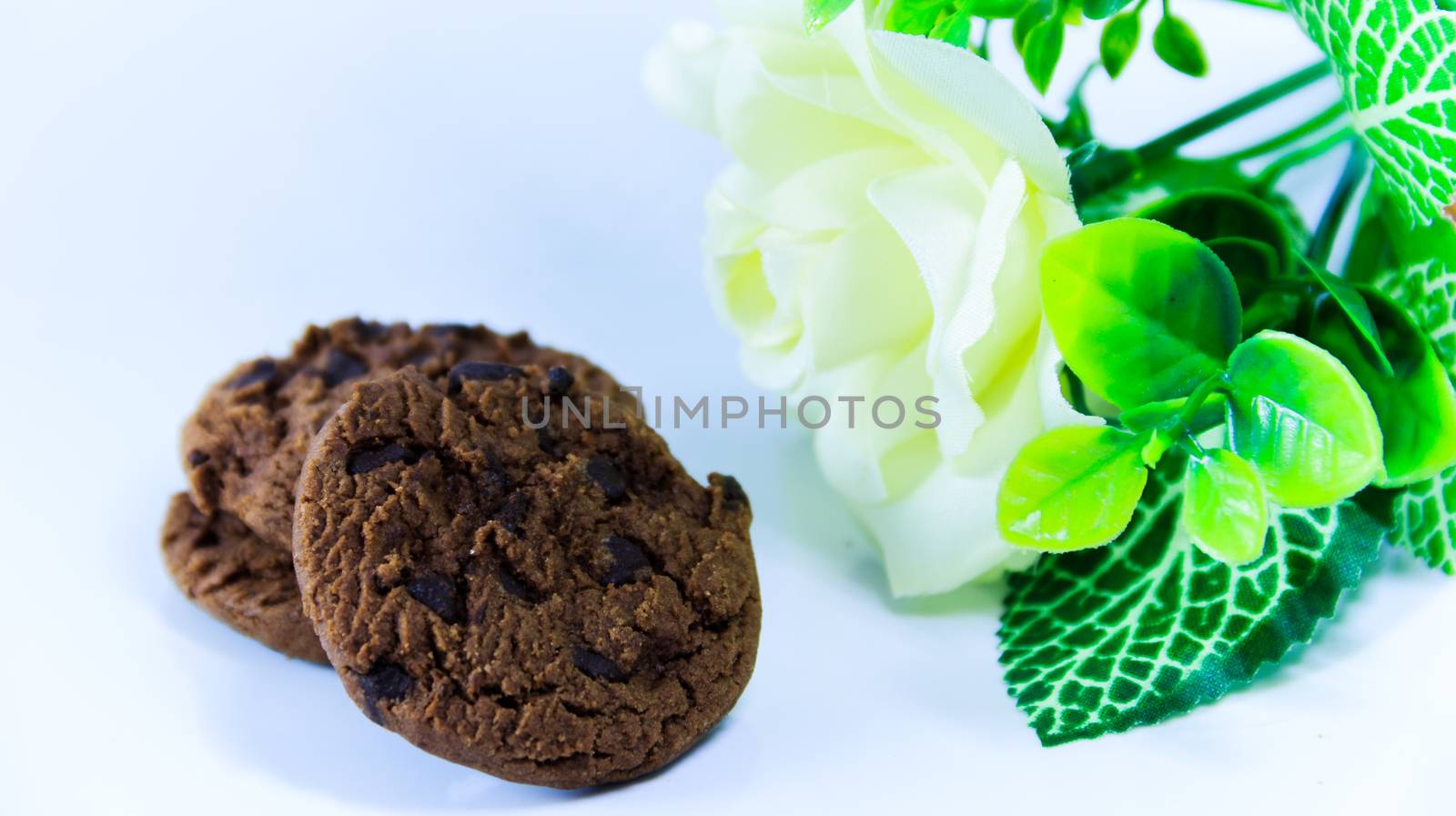 Chocolate chip cookies and white rose on white background by suriyaph