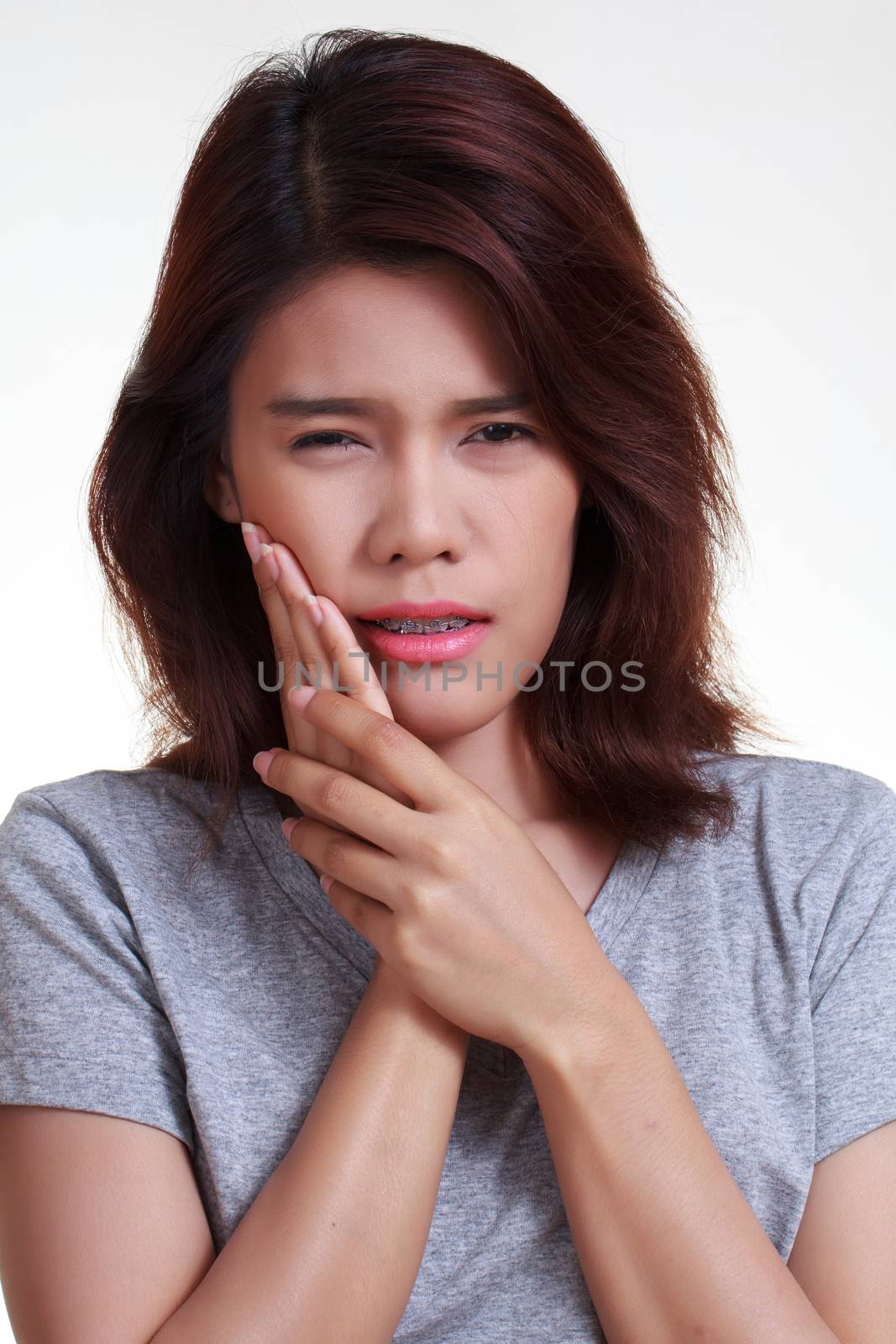 Teen woman pressing her bruised cheek with a painful expression as if she's having a terrible tooth ache.