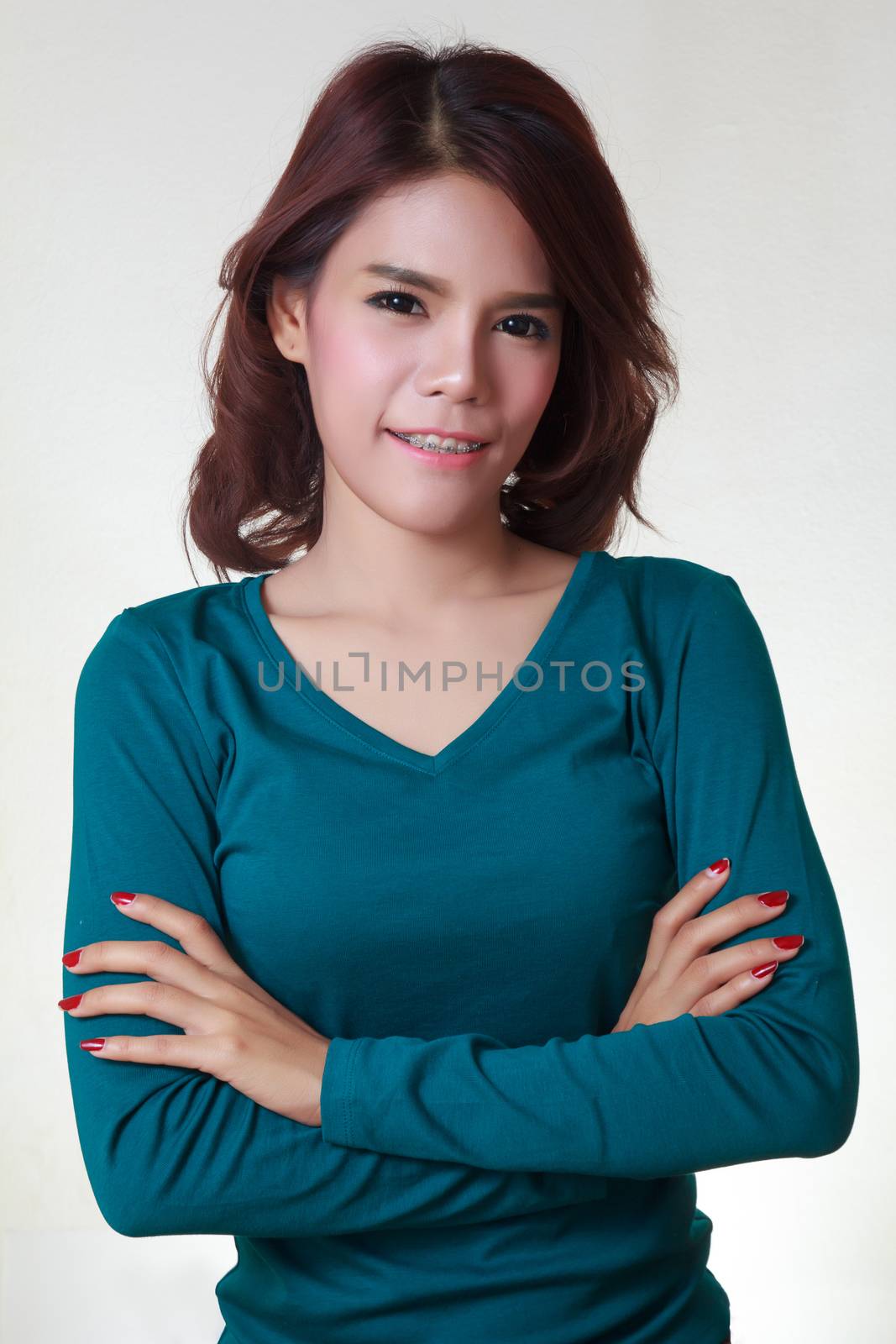 Young woman crossed arms standing against white. Confident pose