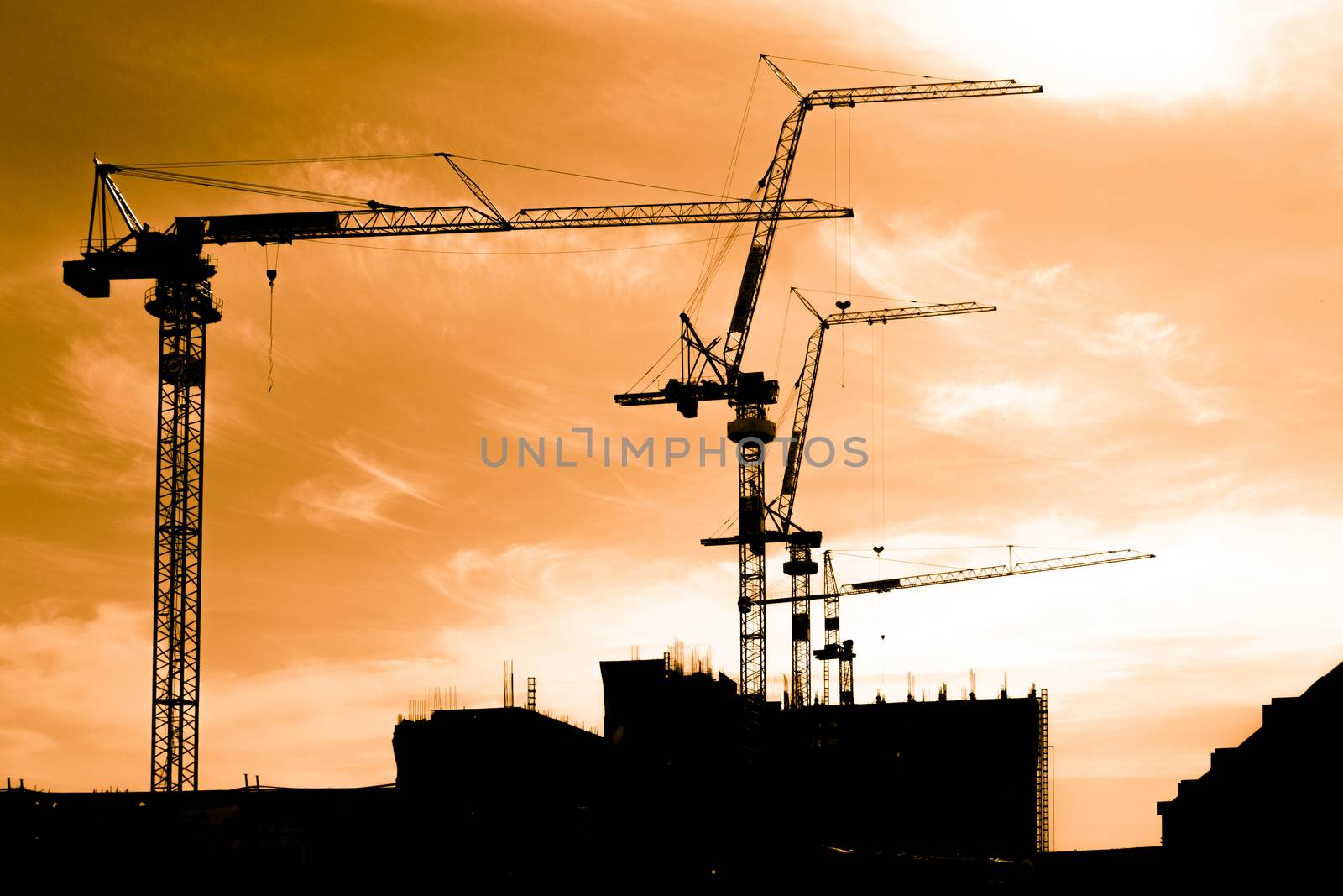 Silhouette of construction workers on scaffold working under a hot sun