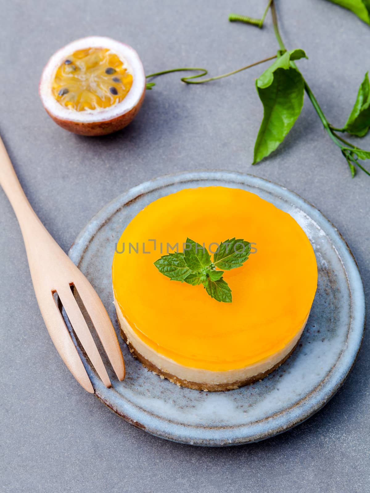 Passion fruit cheesecake with fresh mint leaves on dark concrete background. Passion fruit cheesecake setup with Passion fruit leaves and fresh Passion fruit . Selective focus depth of field.