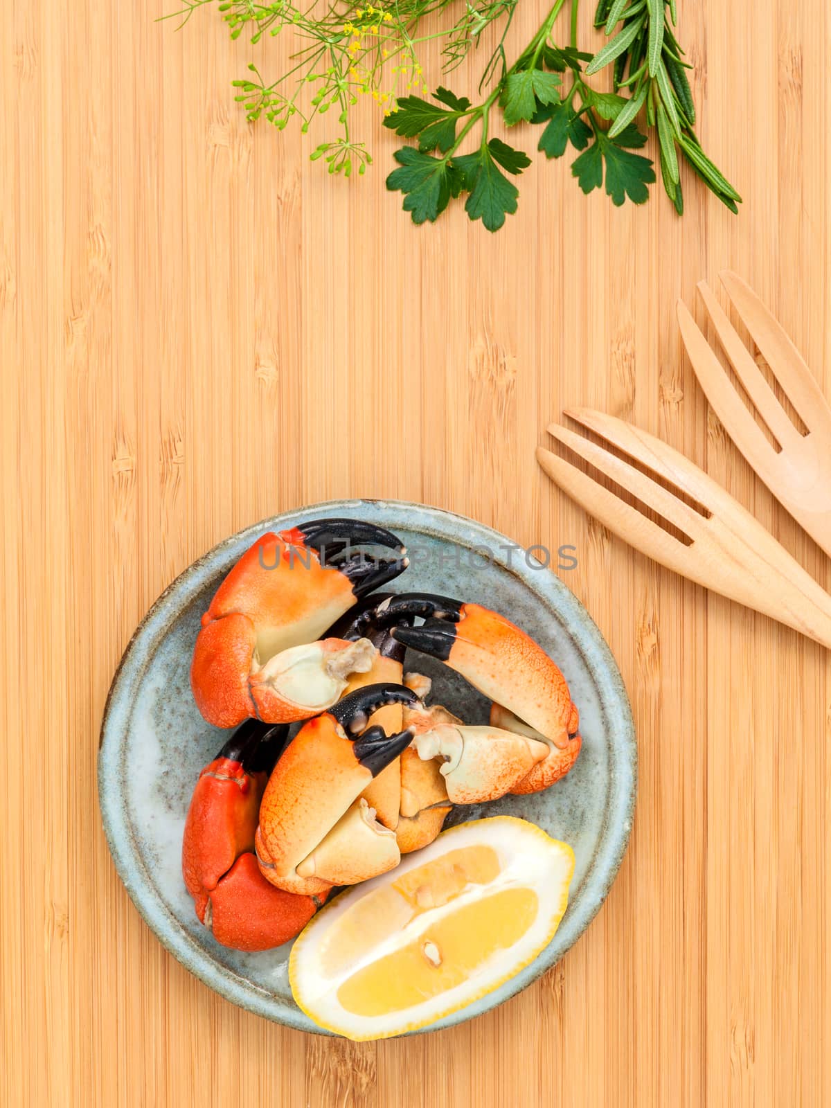 Fresh steamed red crabs leg in bowl . Red crabs leg with ingredients. Steamed red crabs leg with herbs Fennel ,parsley,rosemary,lemon and mint with fork on wooden cutting board.