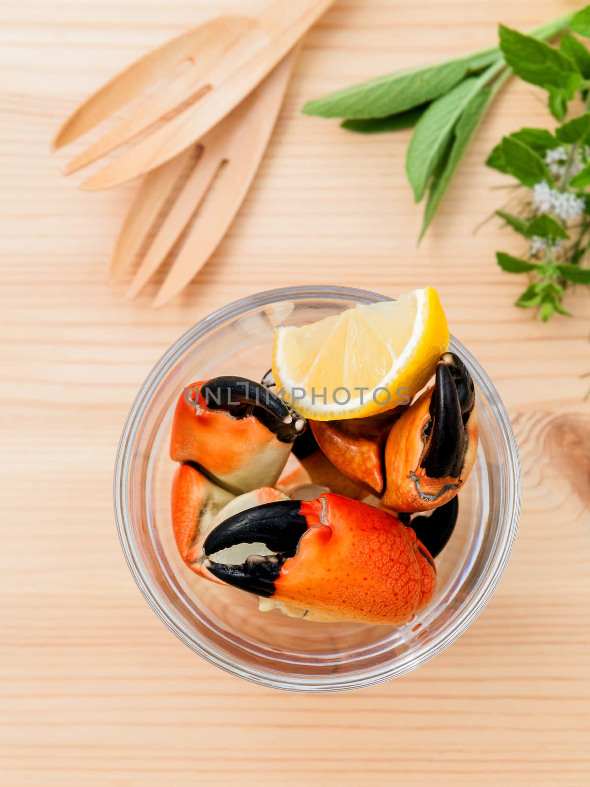 Fresh steamed red crabs leg in glass bowl . Red crabs leg with ingredients. Steamed red crabs leg with herbs Fennel ,parsley,rosemary,lemon and mint with fork on wooded background.