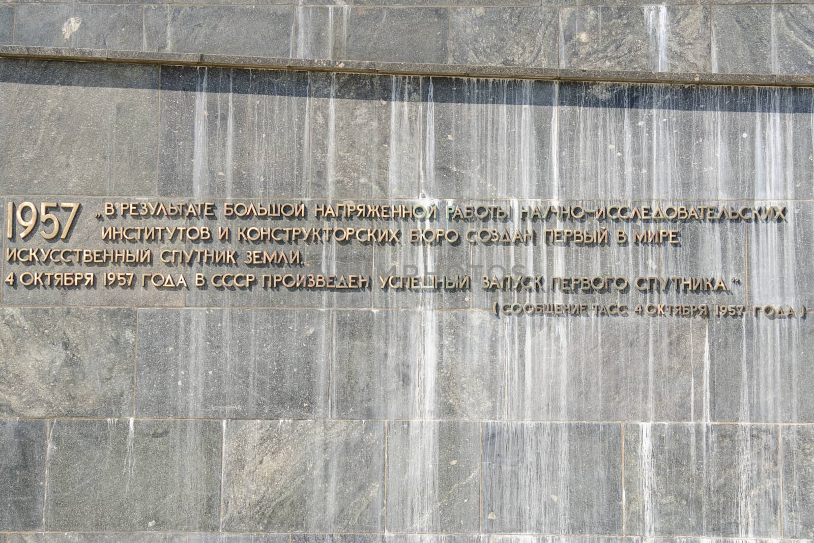 Moscow, Russia - August 10, 2015: The inscription with the TASS report on the withdrawal of artificial earth satellite at the foot of the monument "Conquerors of Space" in Moscow