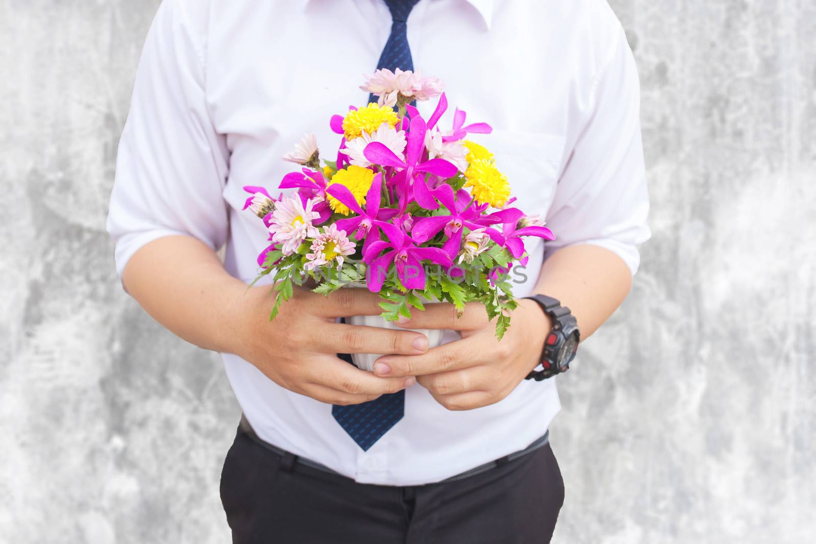 Waiting for his girlfriend. Close up of handsome young man holding bouquet of flowers stand in front of the concrete wall .