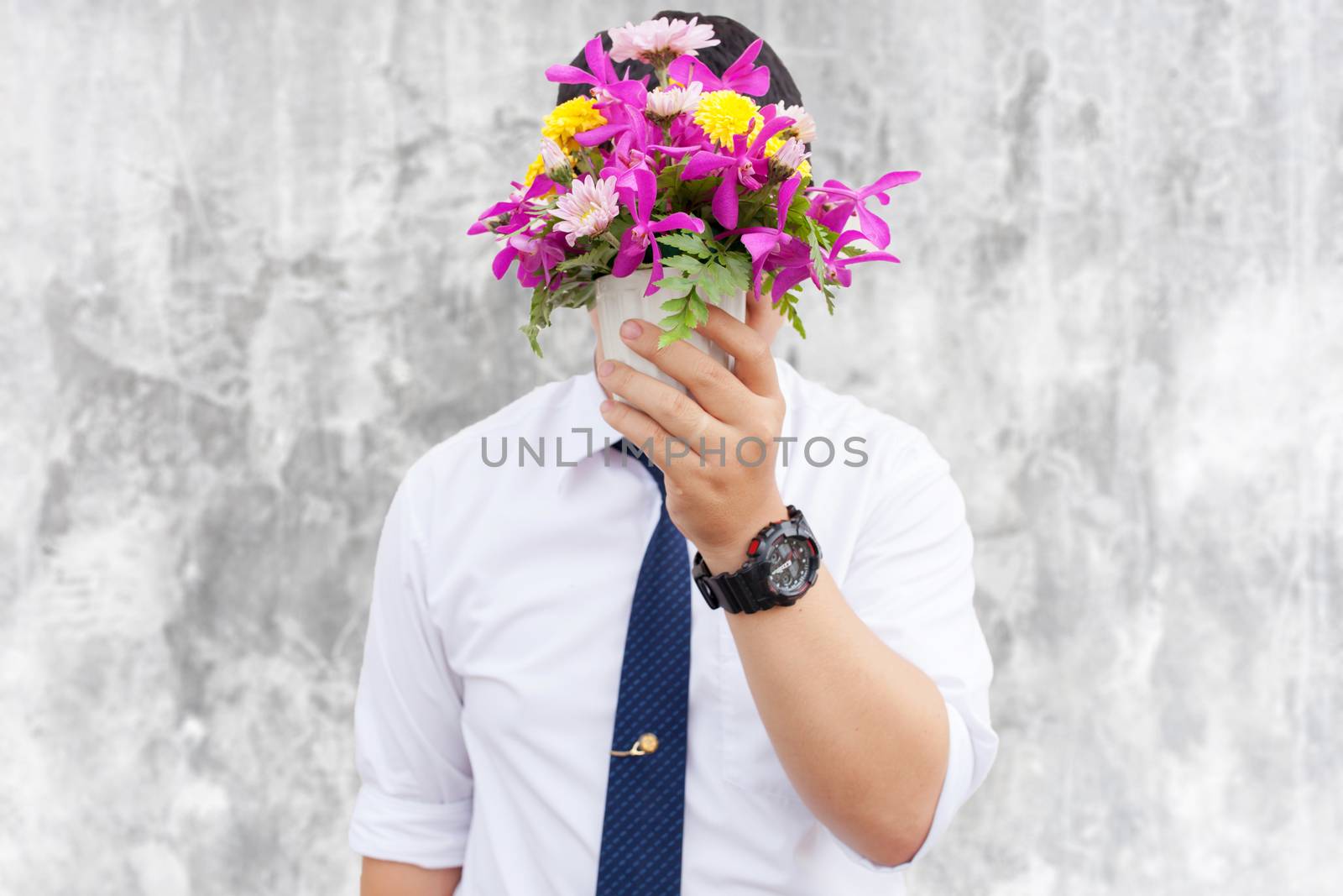 Waiting for his girlfriend. Close up of handsome young man holding bouquet of flowers stand in front of the concrete wall .