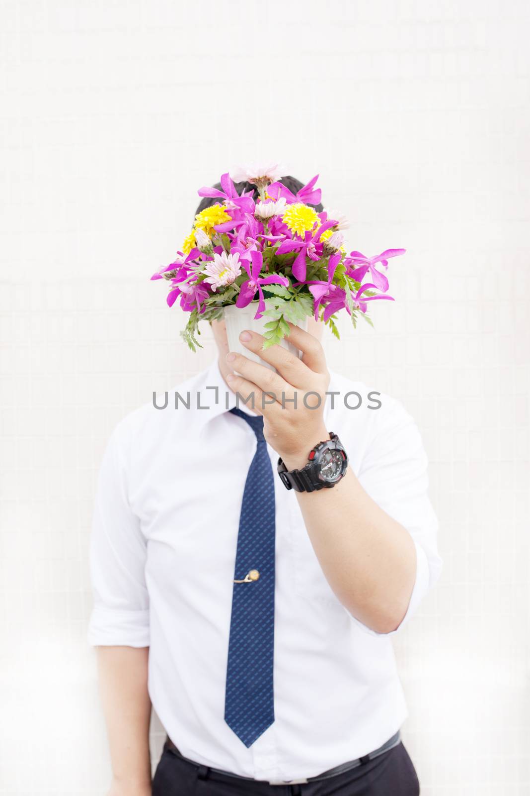 Waiting for his girlfriend. Close up of handsome young man holding bouquet of flowers stand in front of the concrete wall .