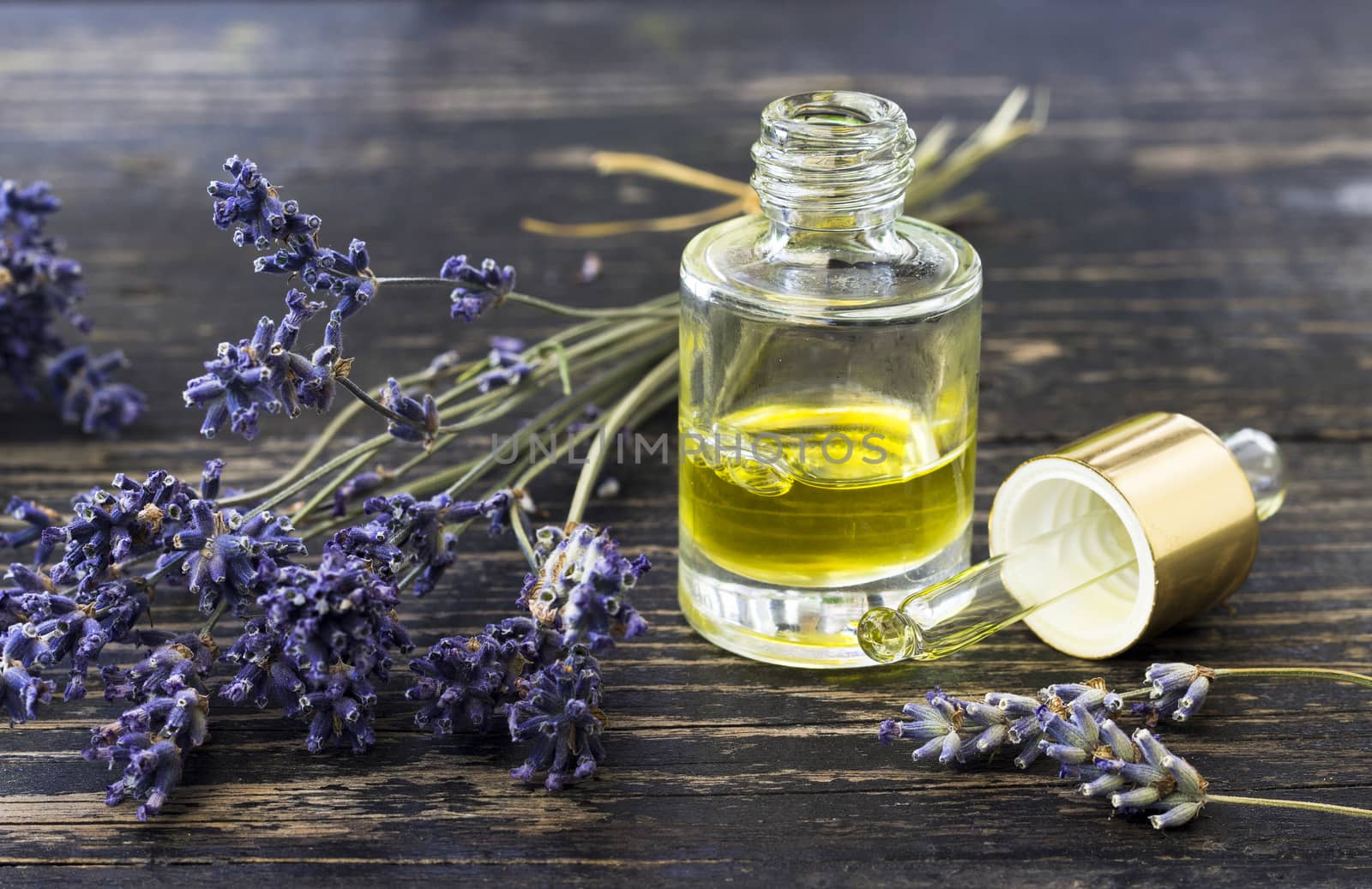 Bottle of lavender oil and bunch of lavender flowers