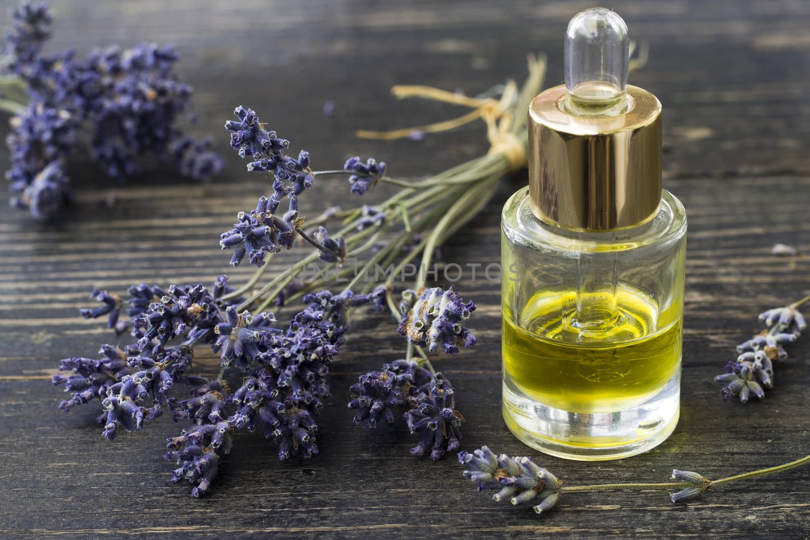 Herbal oil and lavender flowers on wooden background.Selective focus