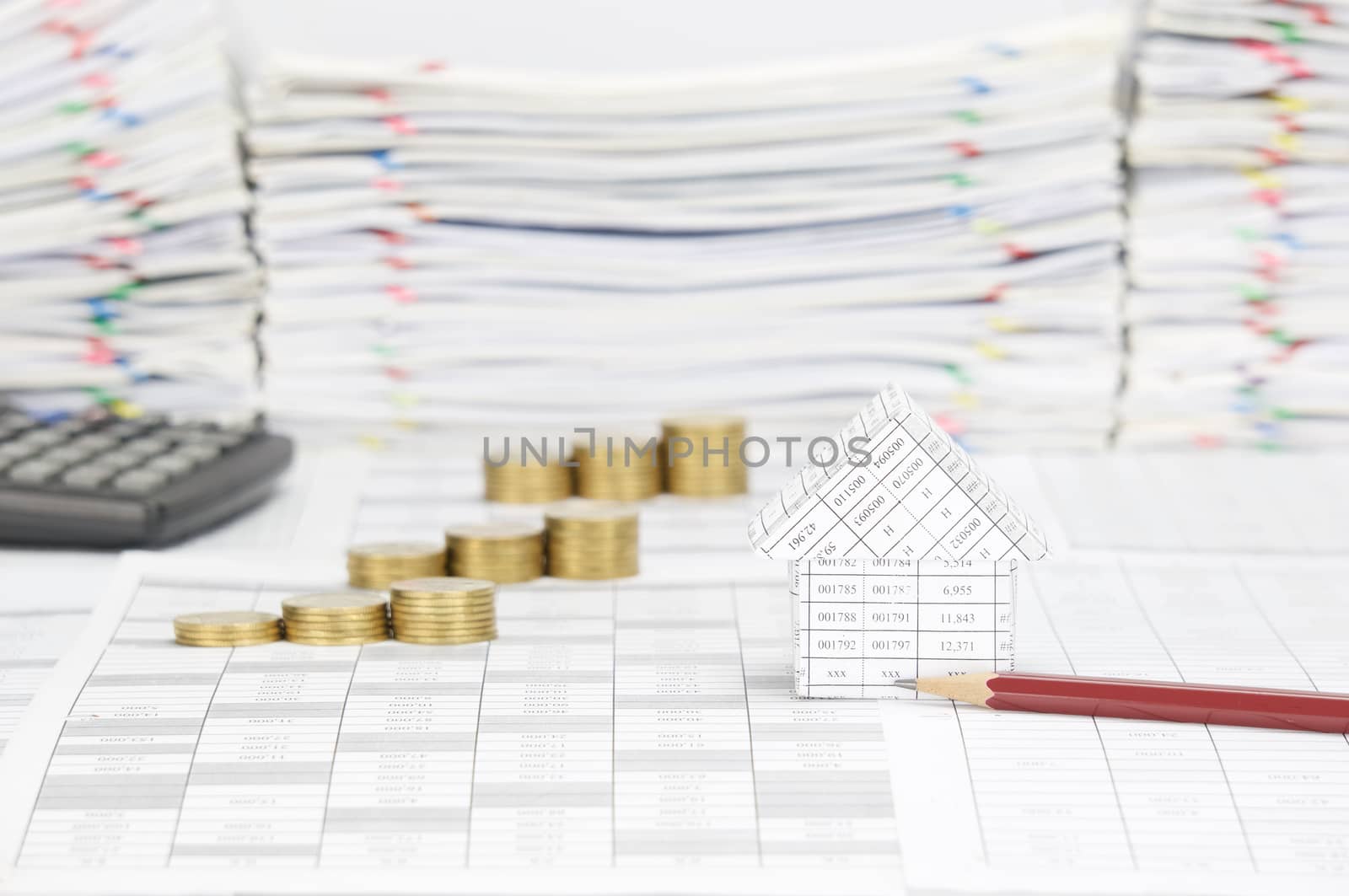 House and brown pencil on finance account have blur step pile of gold coins with calculator and overload of paperwork with colorful paperclip as background.