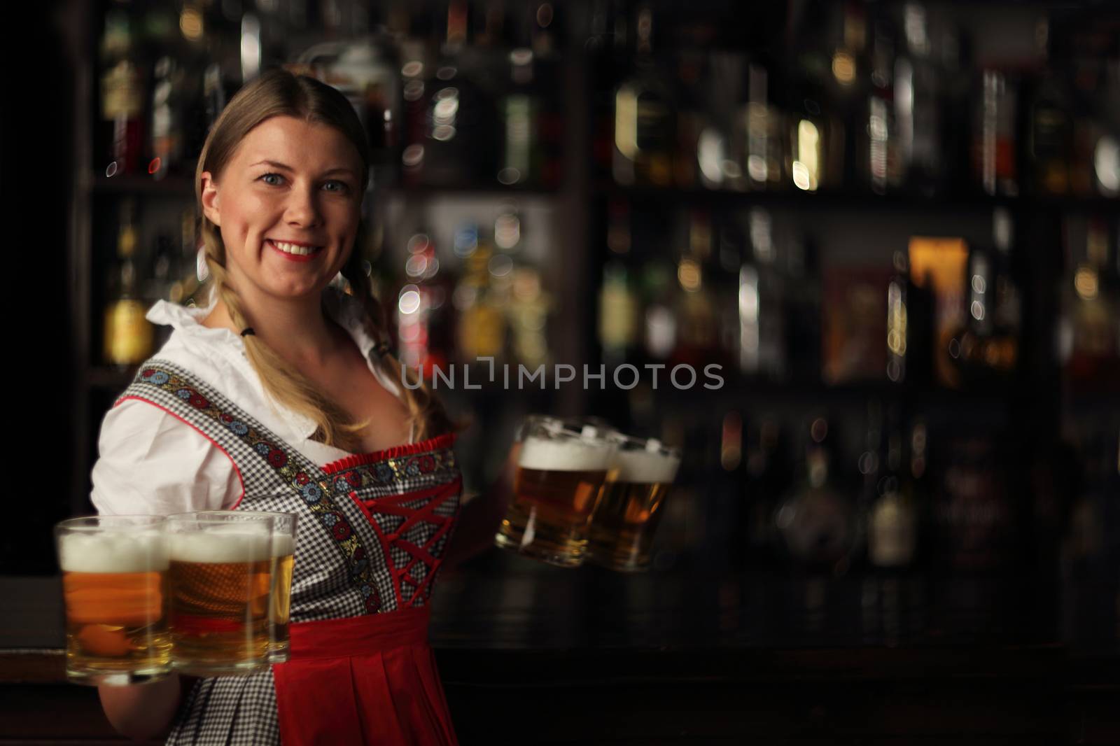 Pretty oktoberfest blonde woman holding beer bugs in bar