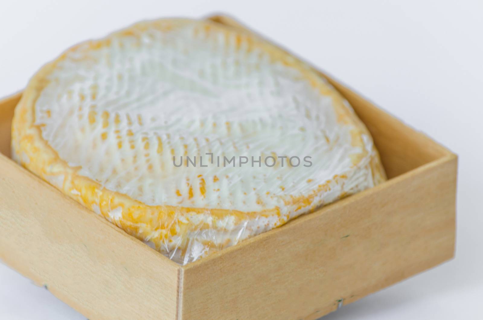 Round white Camembert in a small wooden box.