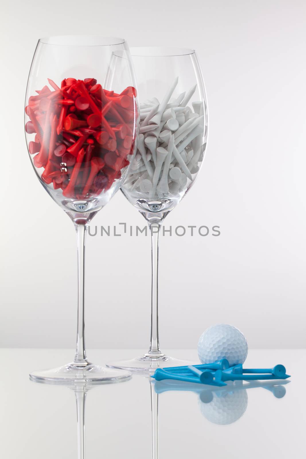 Two glasses of wine and golf equipments on the white background