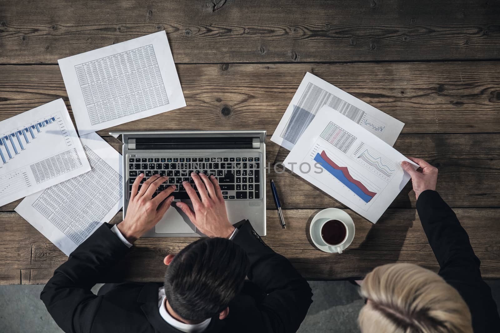 Businessman working on laptop with financial documents, top view