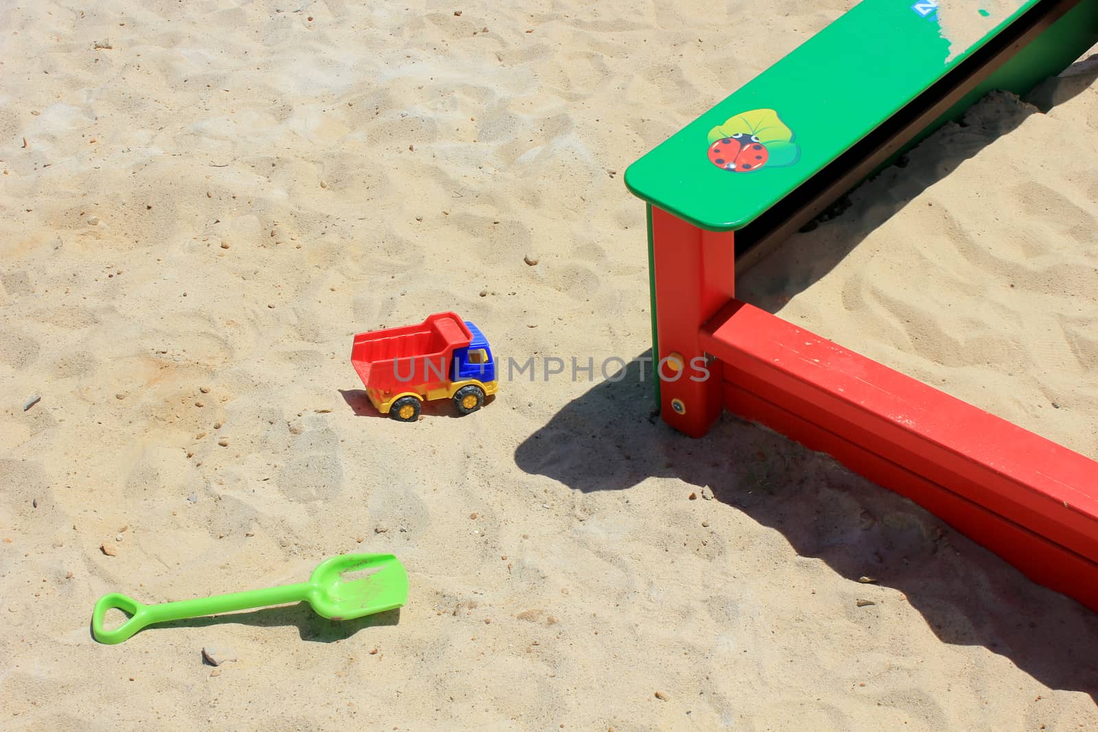 Bright children's sandbox with yellow sand and plastic toys