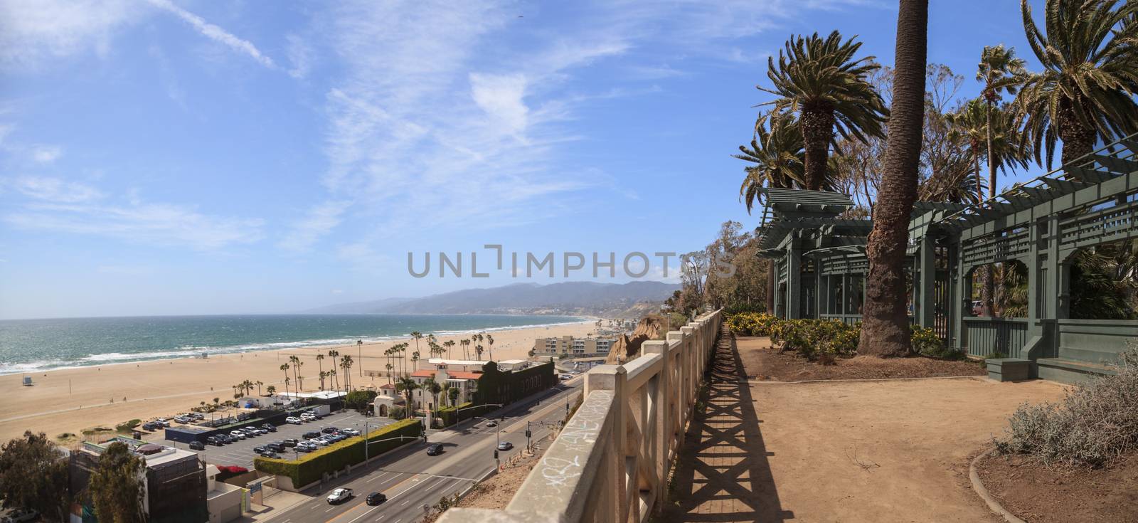 Along the Santa Monica coastline with a blue sky over the white sand of the beach in Southern California, United States.