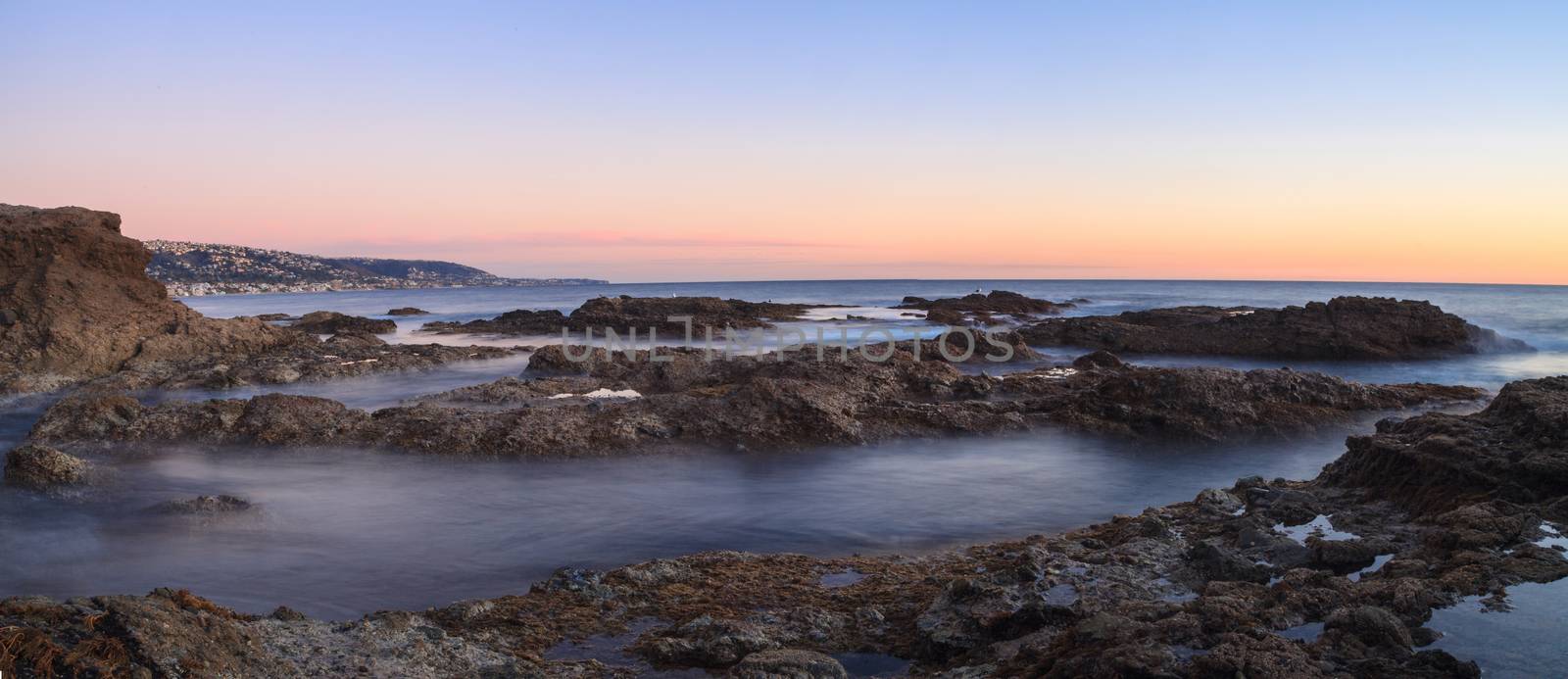 Long exposure of sunset over rocks, giving a mist like effect over ocean in Laguna Beach, California, United States