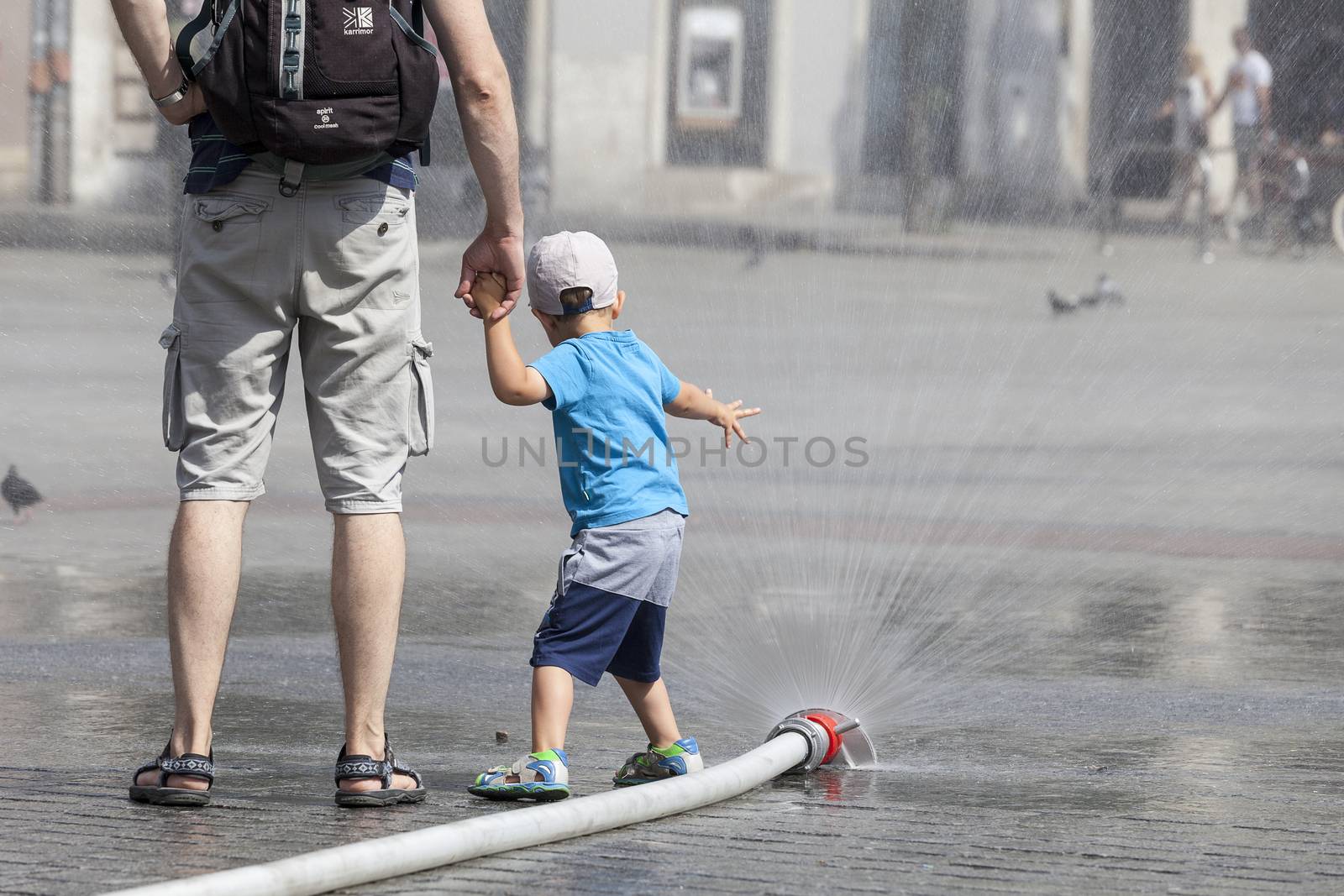 KRAKOW, POLAND - June 26, 2016 : People using  water curtain on main Market Square in sunny hot day in summer.Curtains  are placed by  firefighters in the big heat in several places in the city