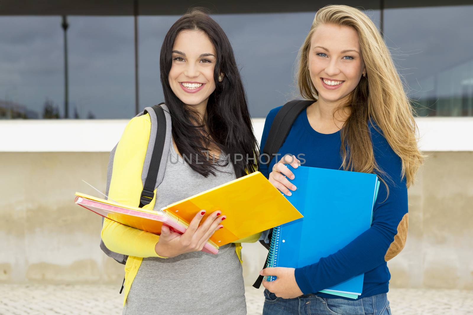 Two happy and beautiful teenage students in the school 