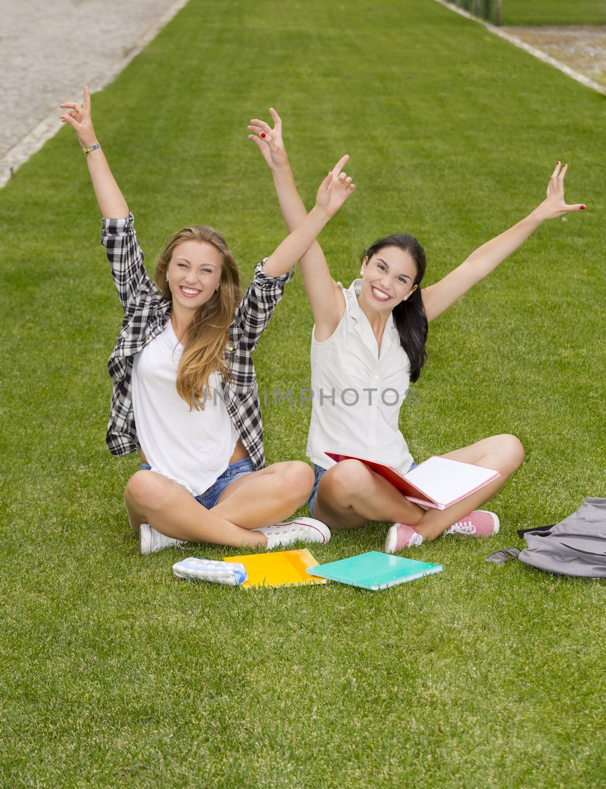 Happy best friends sitting on the grass and having a good time