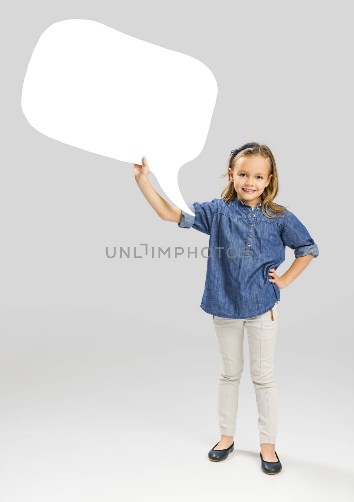 Beautiful little girl holding and showing a speech balloon