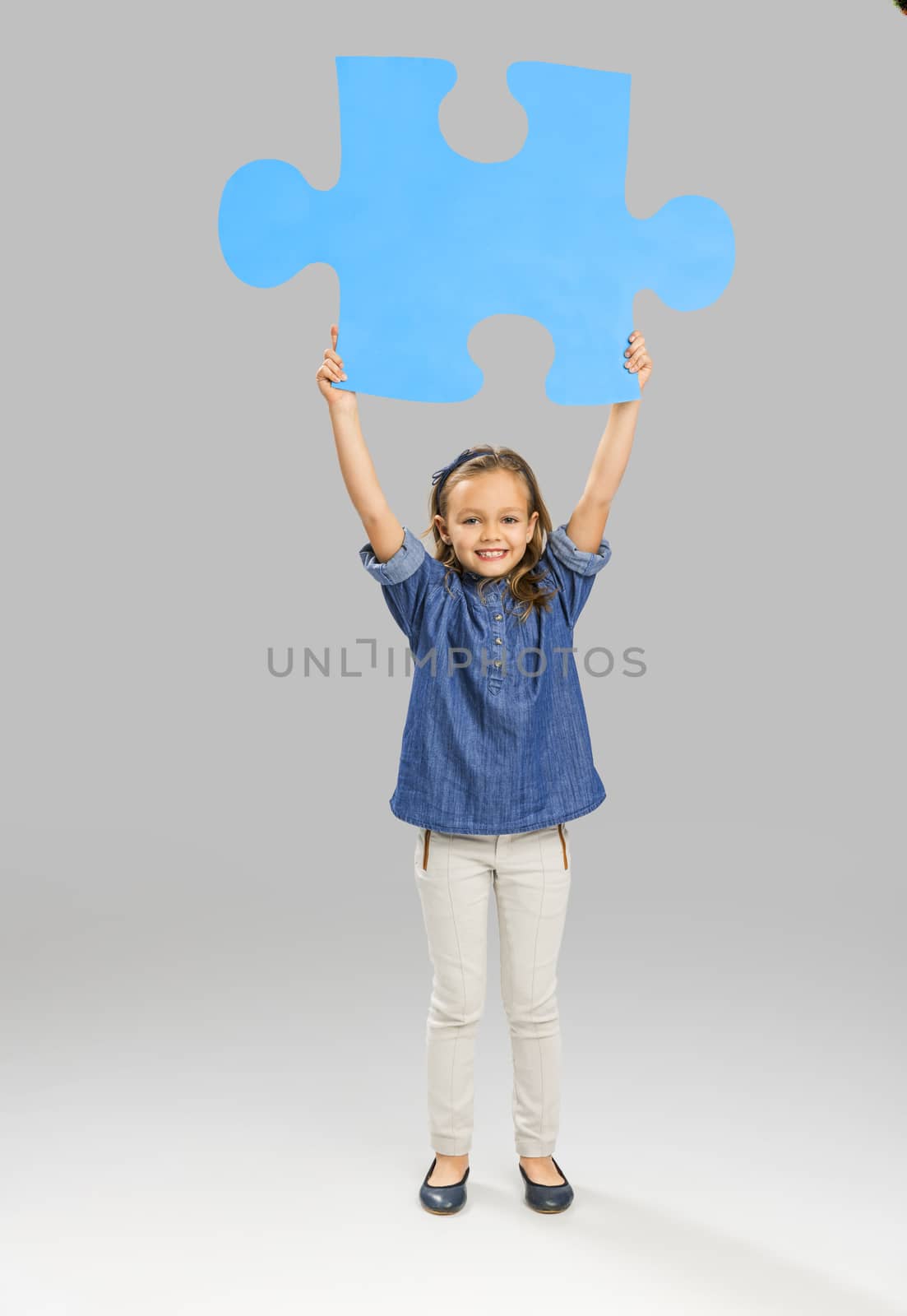 Beautiful little girl holding a big blue Puzzle