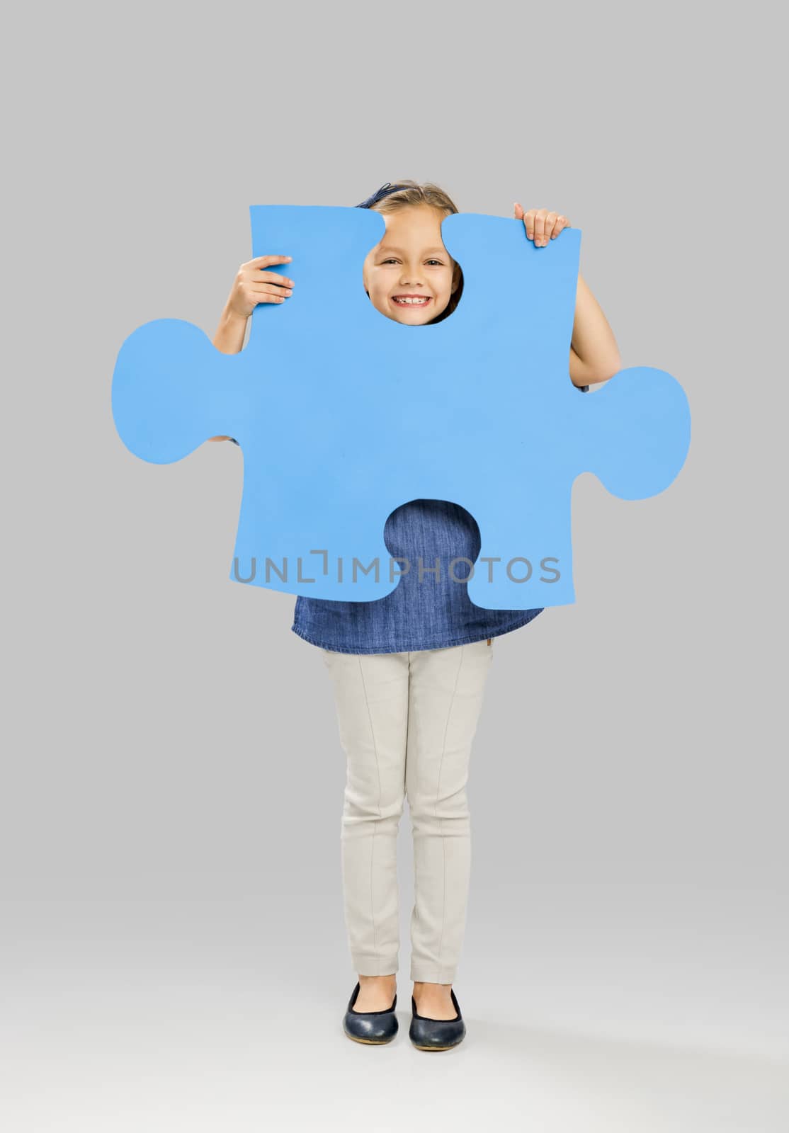 Beautiful little girl holding a big blue Puzzle