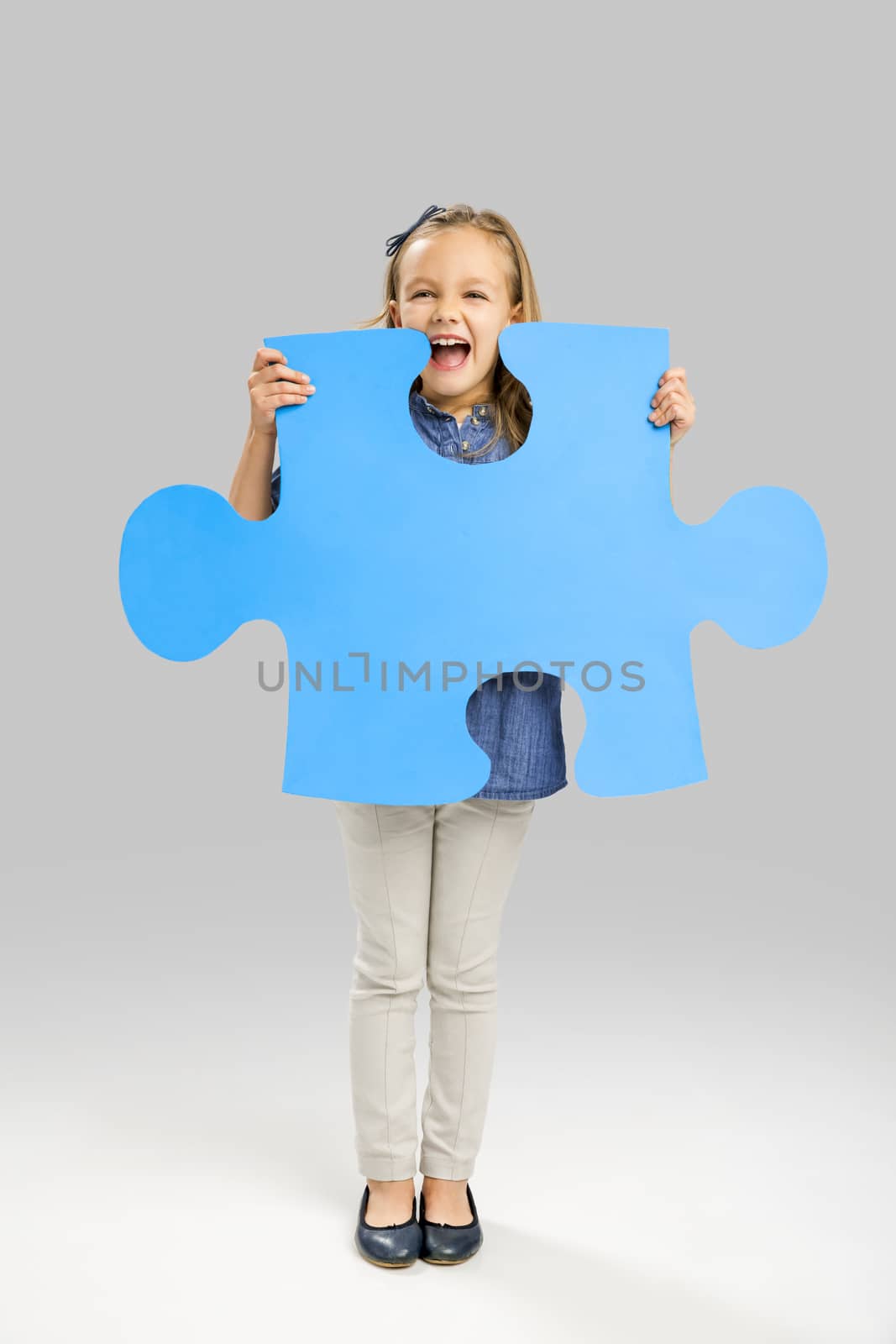 Beautiful little girl holding a big blue Puzzle