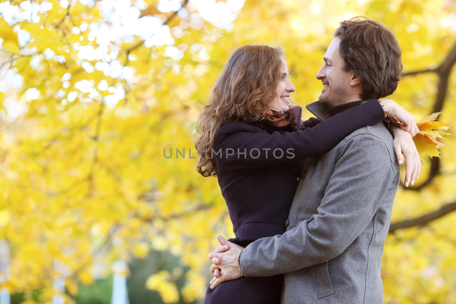 Smiling couple hugging in autumn park with yellow trees