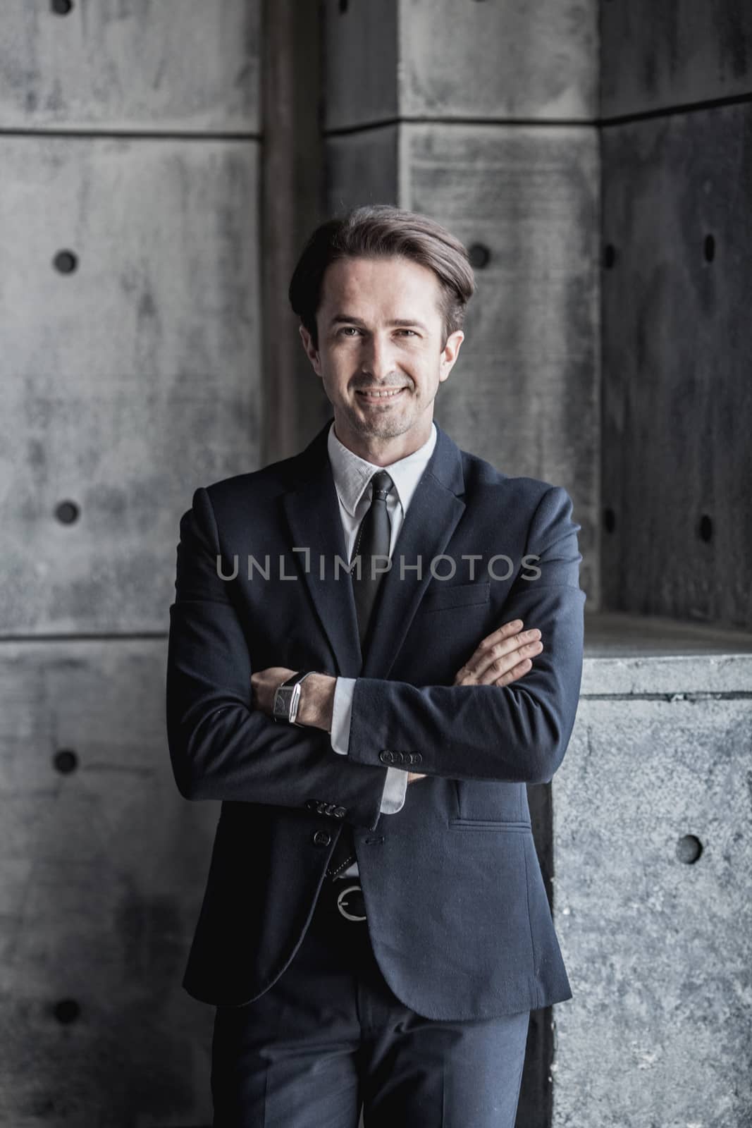 Portrait of smiling businessman in suit over concrete wall background