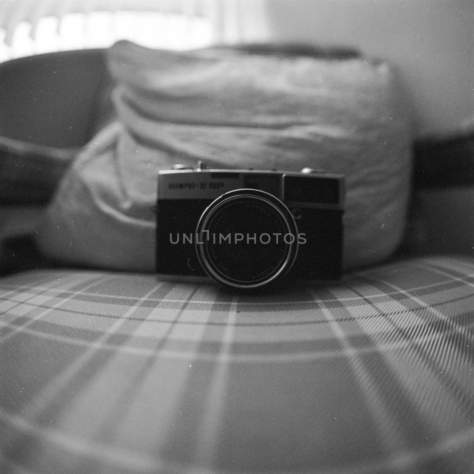 Black and white image of vintage camera on  a bed 