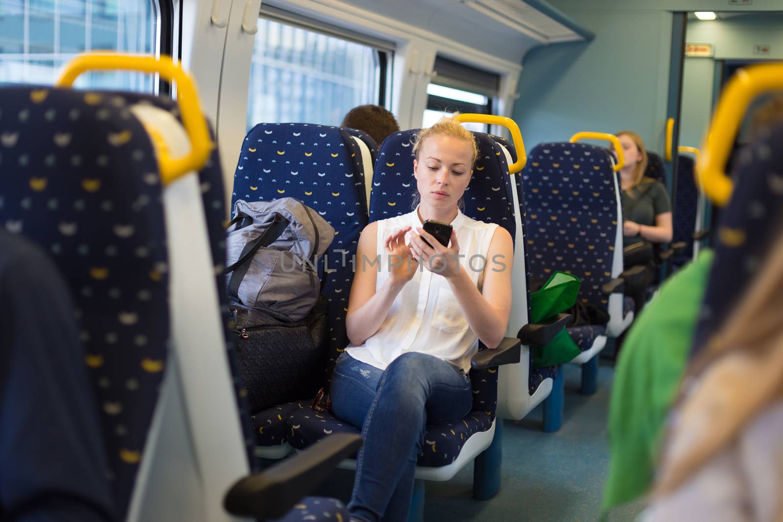 Woman using mobile phone while travelling by train. by kasto