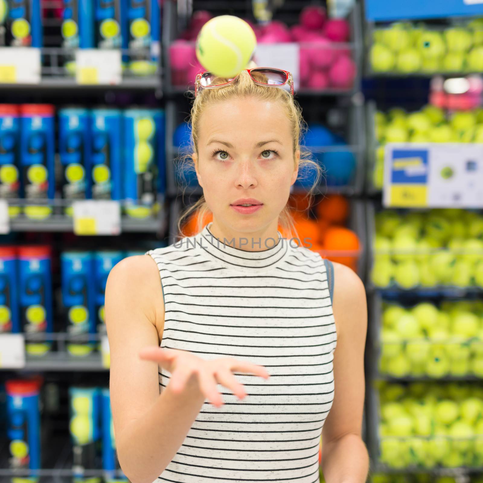 Woman shopping tennis balls in sportswear store. by kasto