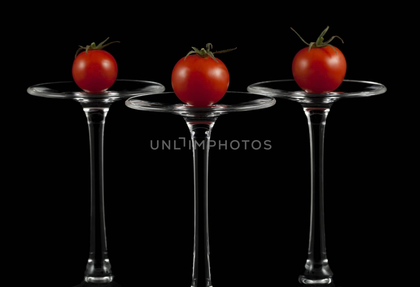Red cherry tomatoes on the overturned glasses.
