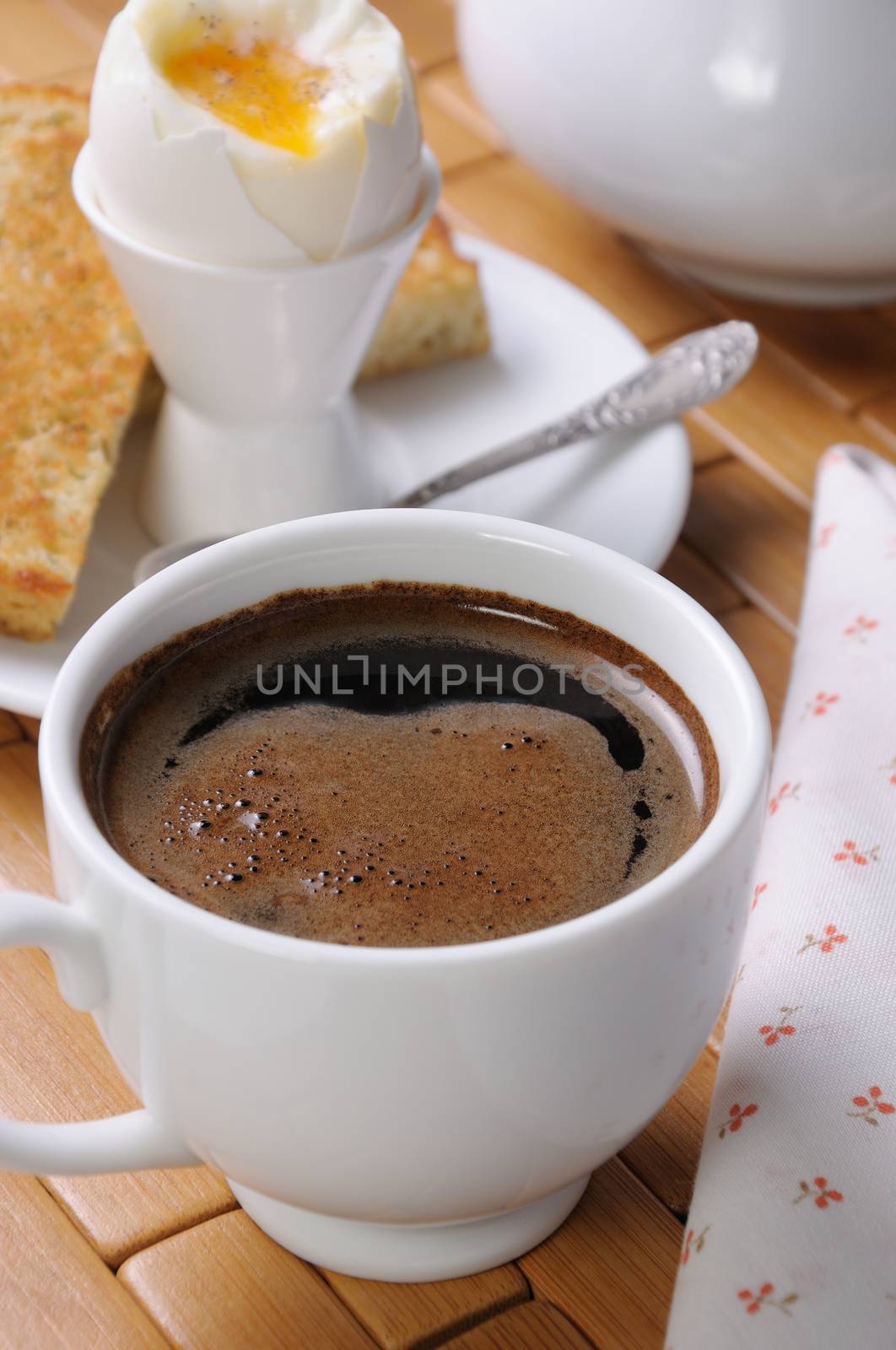 A cup of coffee with a soft-boiled egg and toast for breakfast