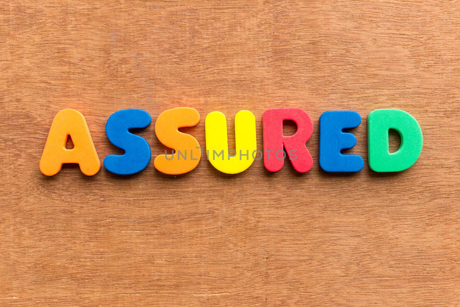 assured colorful word on the wooden background