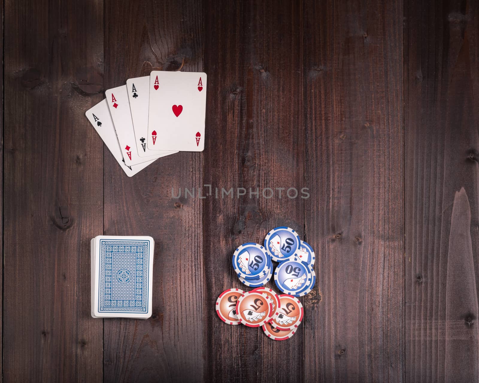 Chips and Four aces vintage poker game playing cards on a weathered wood table,view from above.