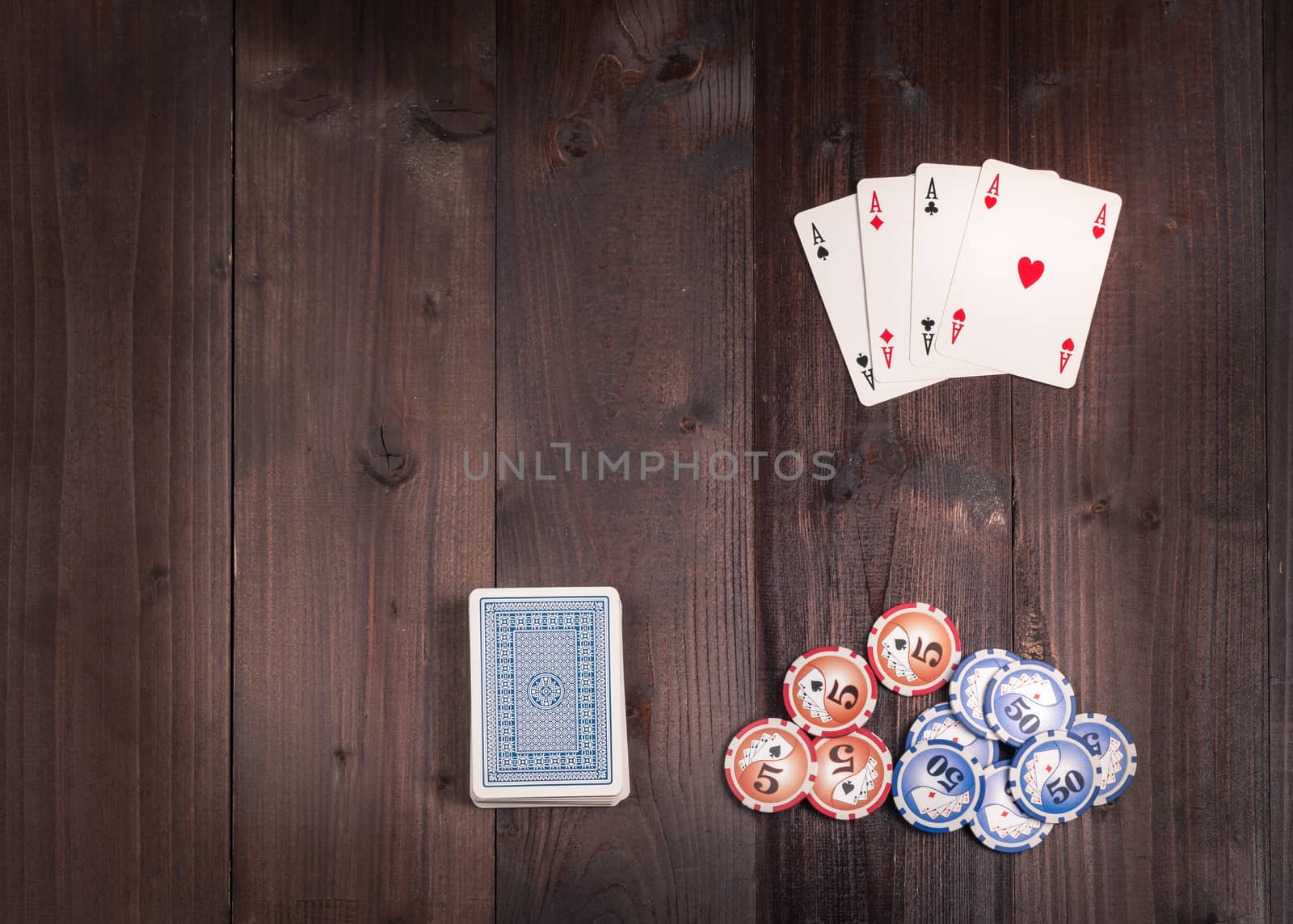 Chips and Four aces vintage poker game playing cards on a weathered wood table,view from above.