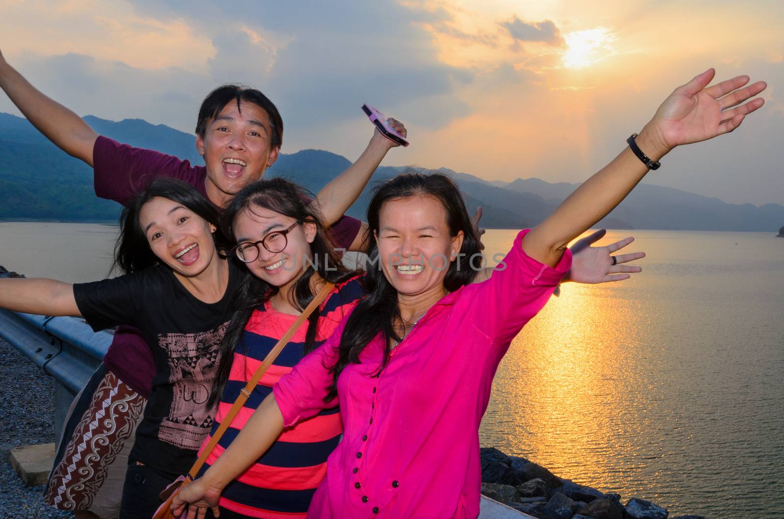 Group of people the family asian tourists are happy during the sunset over the lake at Khuean Sinakharin Dam in Kanchanaburi Province, Thailand