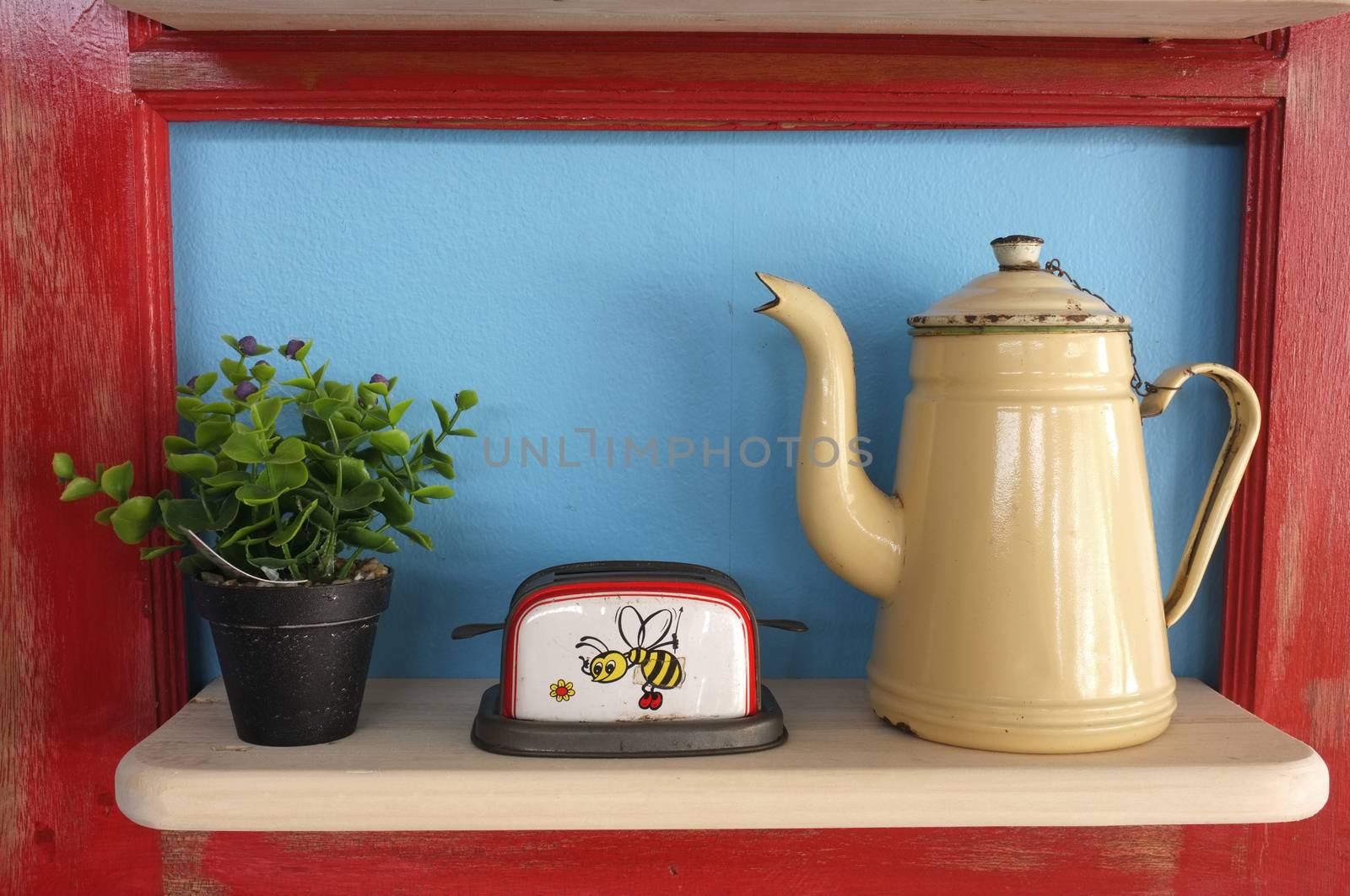 Retro kitchenware and plant pot on wooden shelf, blue background with red frame