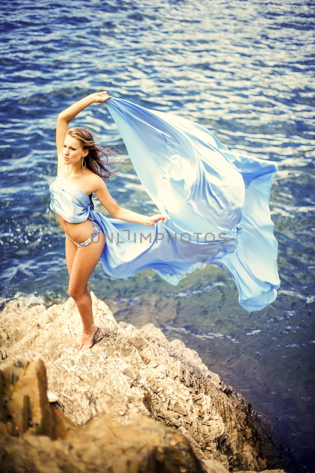 Beautiful girl in a swimsuit standing on a rock.