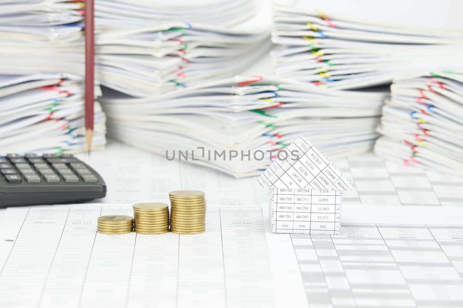 House and step pile of gold coins on finance account have blur pencil place vertical and calculator with pile paperwork of report with colorful paperclip as background.