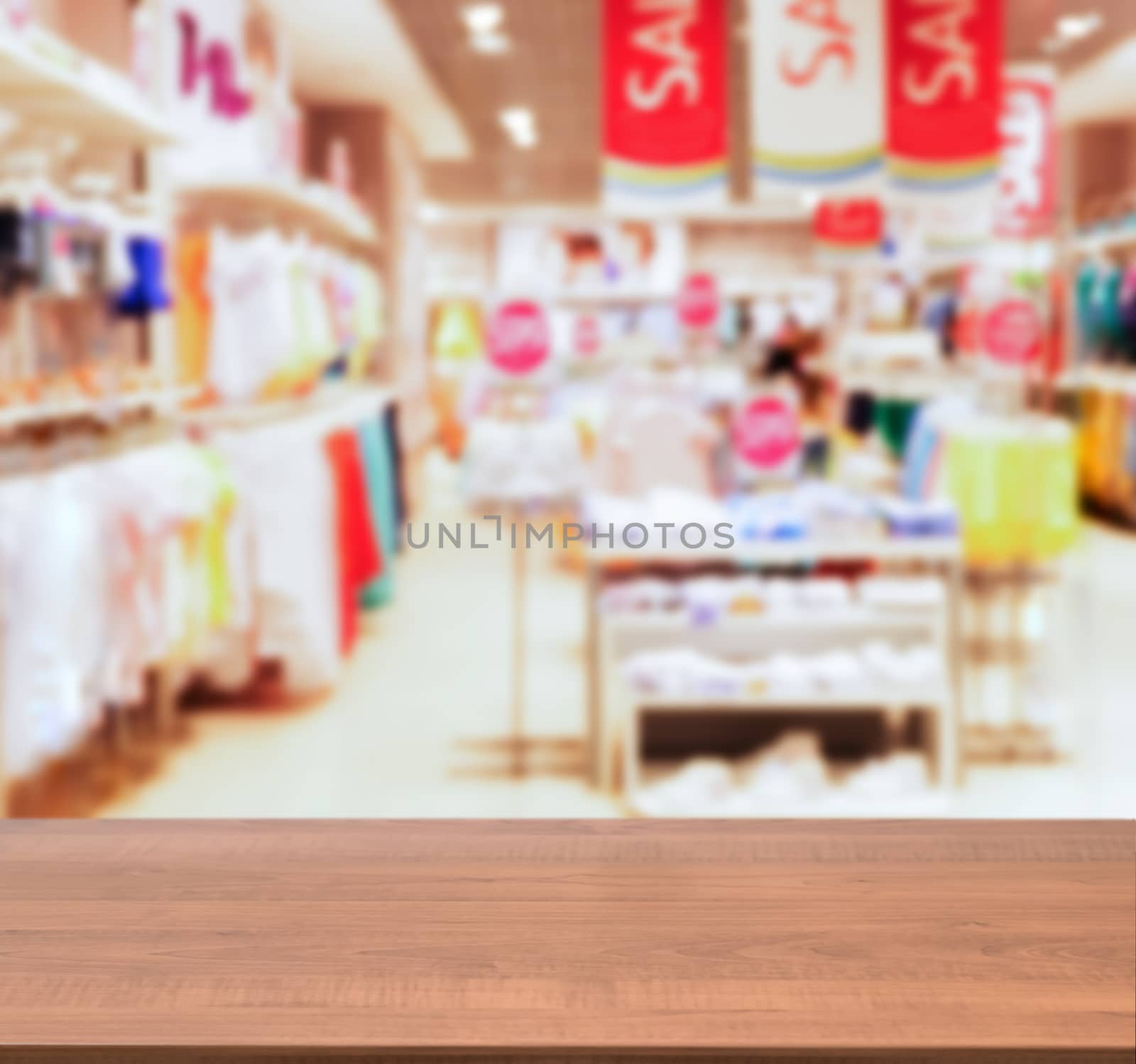 Wooden board empty table in front of blurred background. Perspective dark wood table over blur in kids wear of departament store. Mock up for display or montage your product.