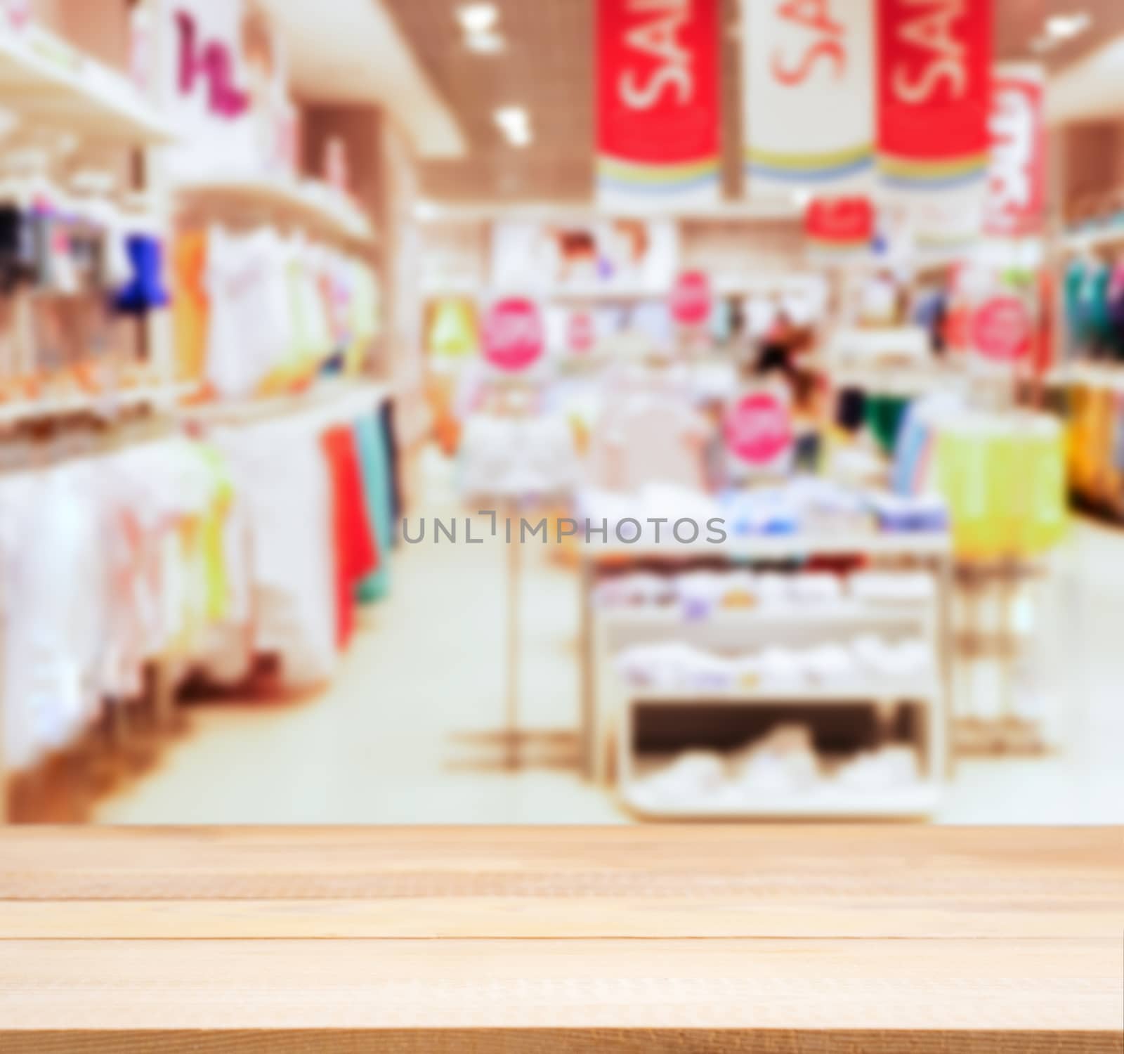 Wooden board empty table in front of blurred background. Perspective light wood table over blur in kids wear of departament store. Mock up for display or montage your product.