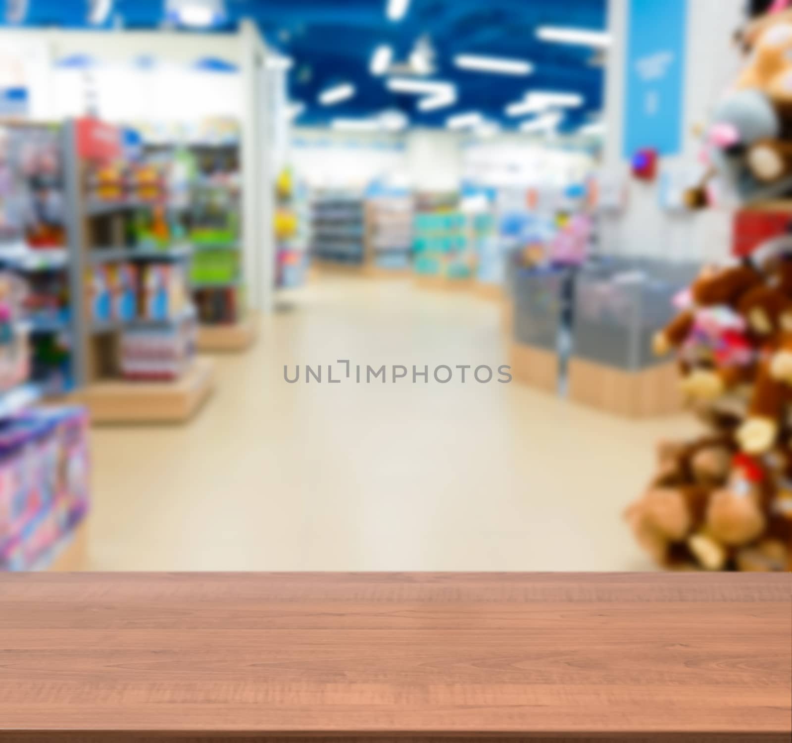 Wooden board empty table in front of blurred background. Perspective dark wood table over blur in kids toy store. Mock up for display or montage your product.