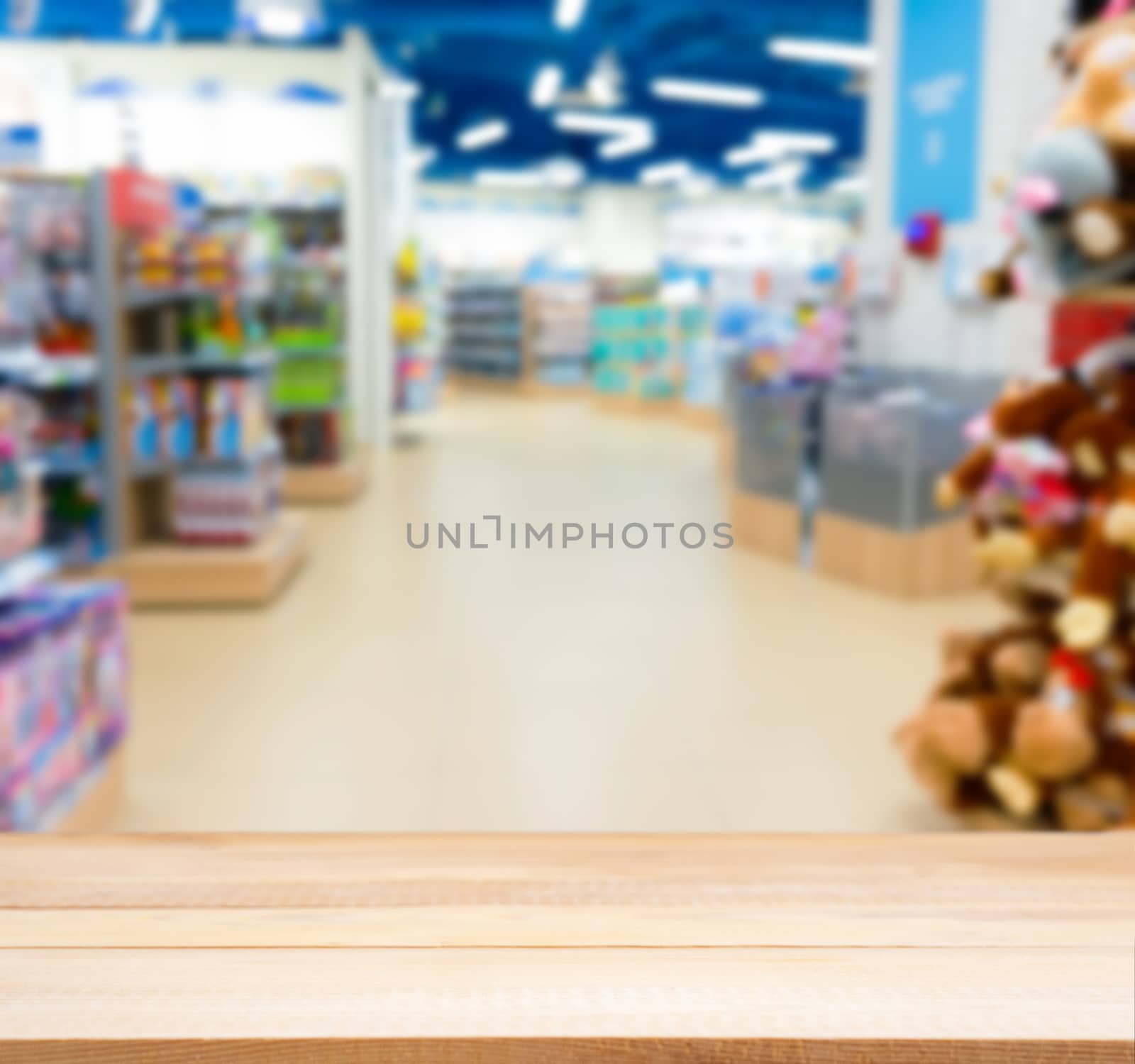 Wooden board empty table in front of blurred background. Perspective light wood table over blur in kids toy store. Mock up for display or montage your product.
