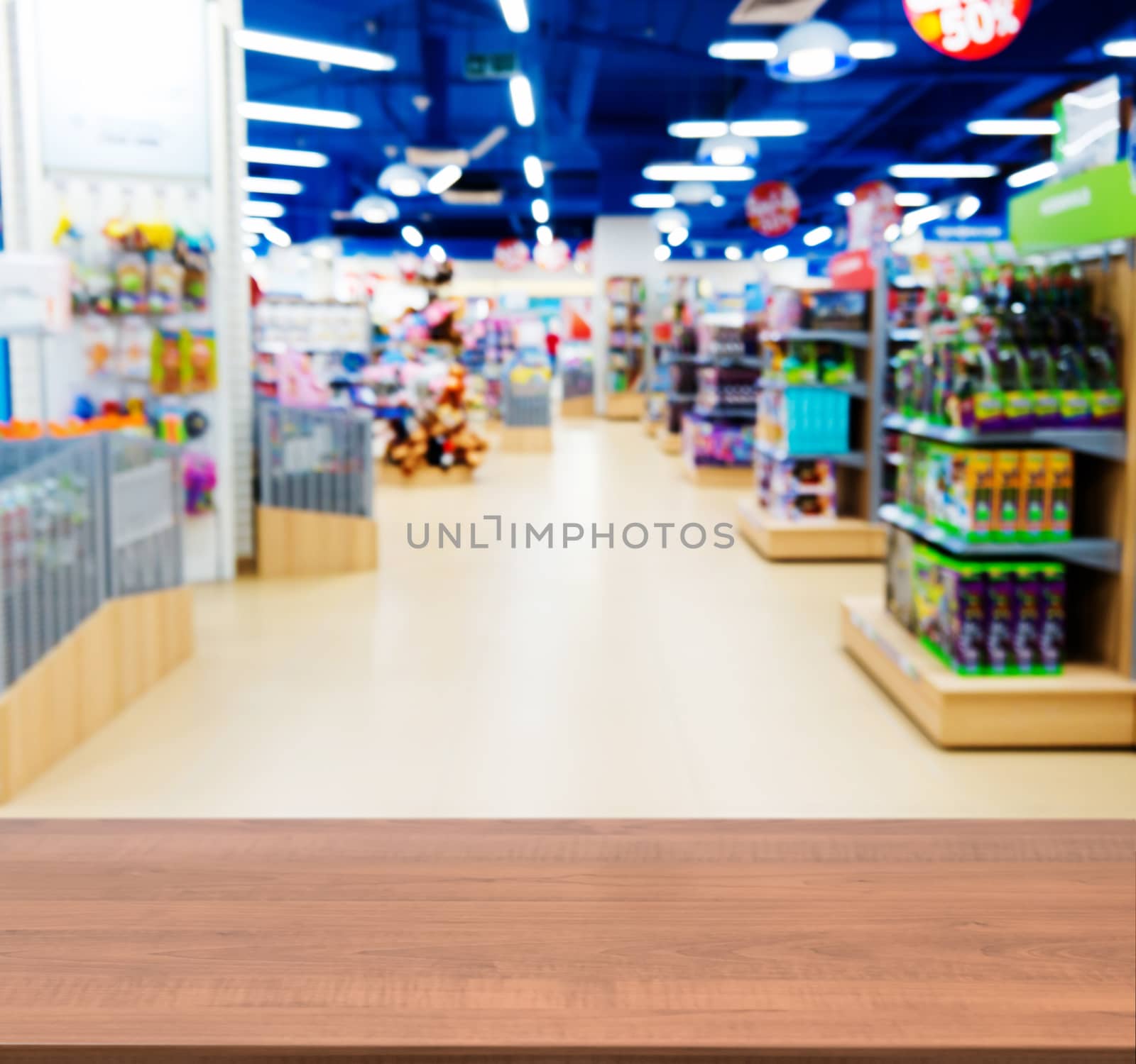 Wooden board empty table in front of blurred background. Perspective dark wood table over blur in kids toy store. Mock up for display or montage your product.