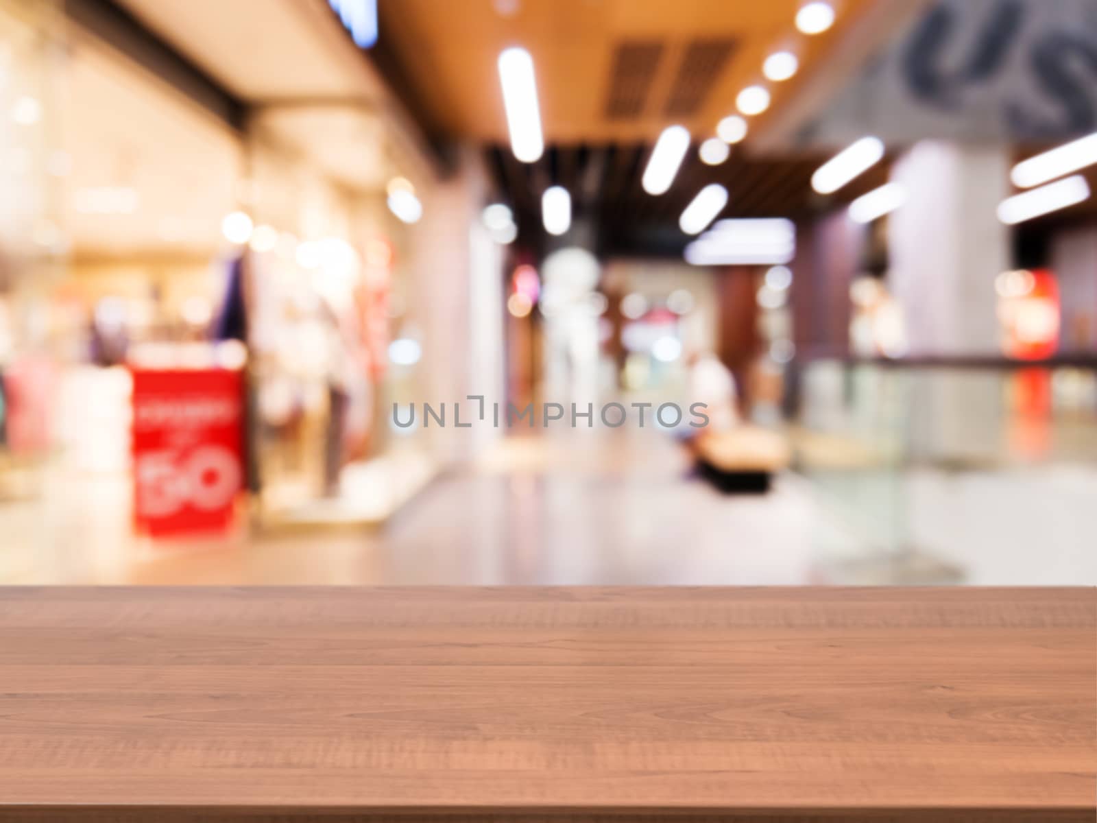 Wooden board empty table in front of blurred background. Perspective dark wood table over blur in shopping mall hall. Mock up for display or montage your product.