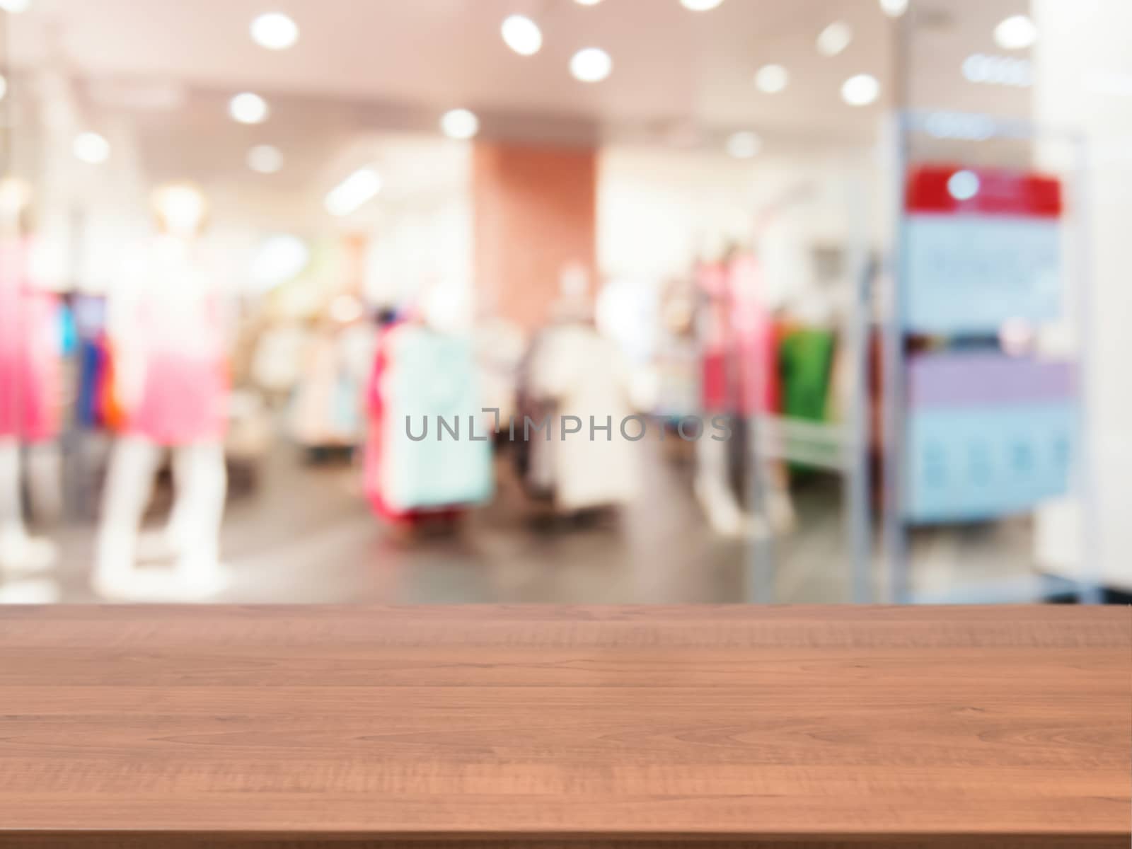 Wooden board empty table in front of blurred background. Perspective dark wood table over blur in dress store. Mock up for display or montage your product.