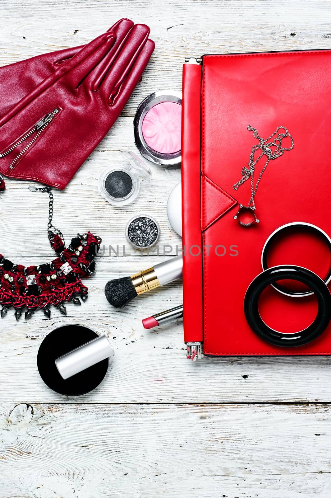 Fashionable ladies handbag with cosmetics and decorations on light background
